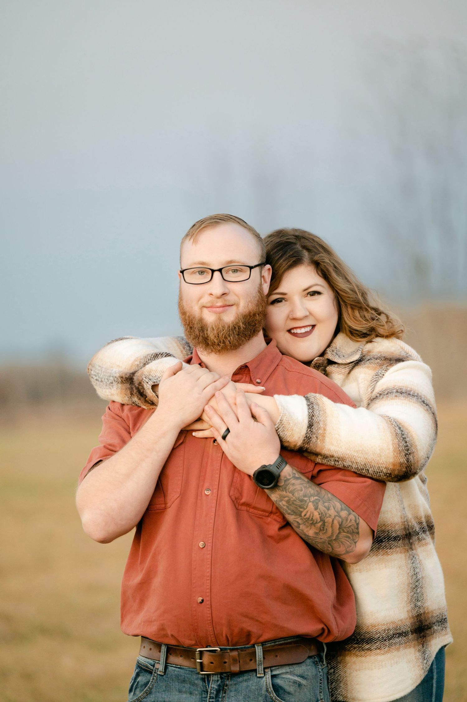 A couple shares a joyful embrace while wearing coordinating outfits in an outdoor autumn setting. St cloud area engagement photos.