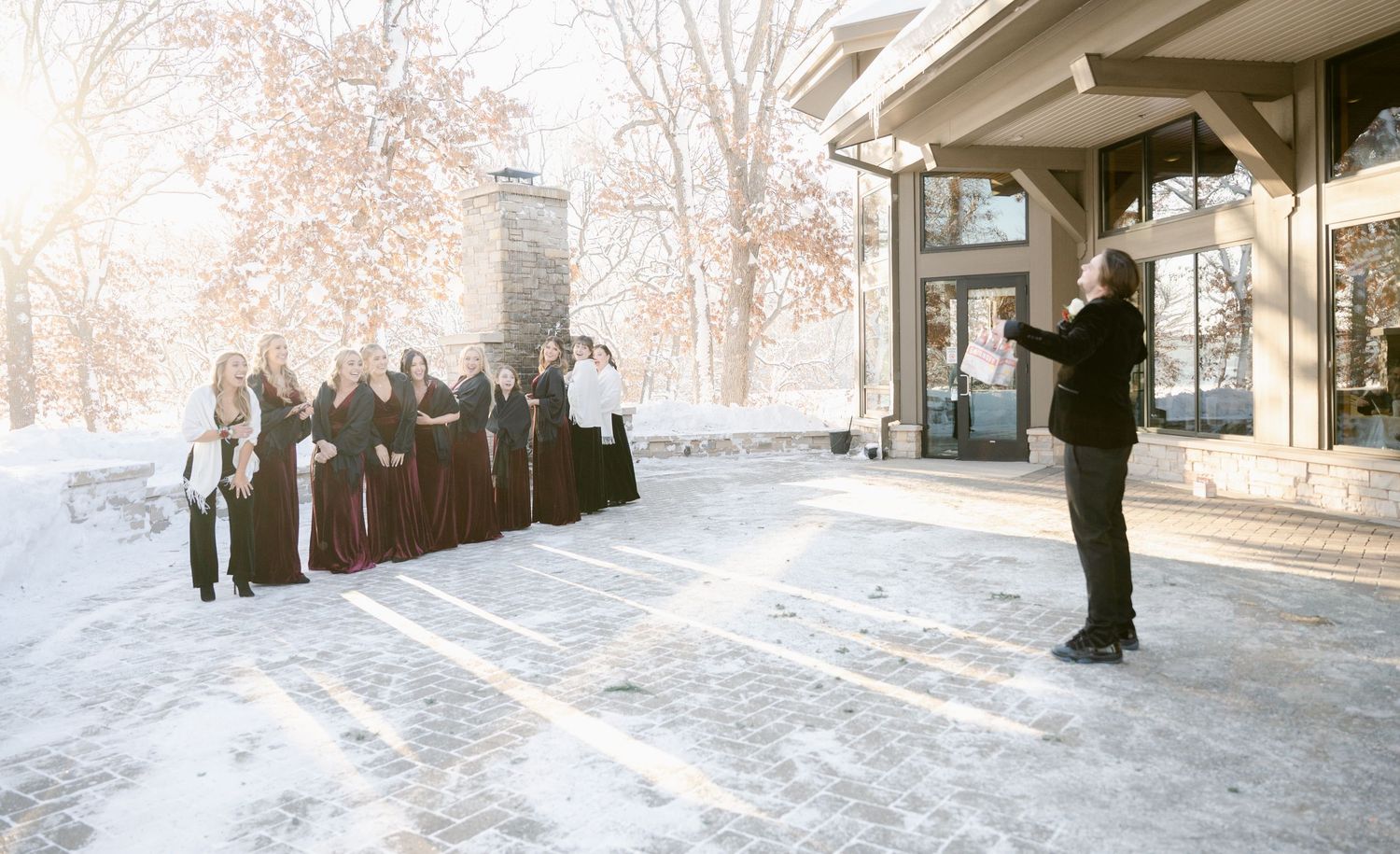 A wedding party poses for photos outdoors in the snow during a winter photo session. St Anthony Weddings