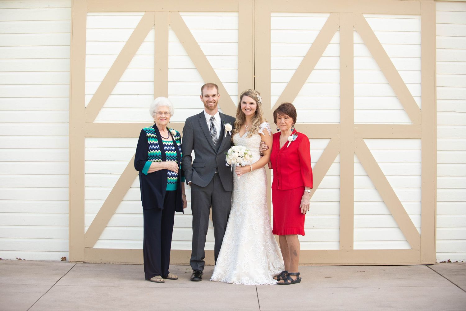 Small family group poses for formal wedding photo against geometric white wall backdrop. Milaca Minnesota Weddings