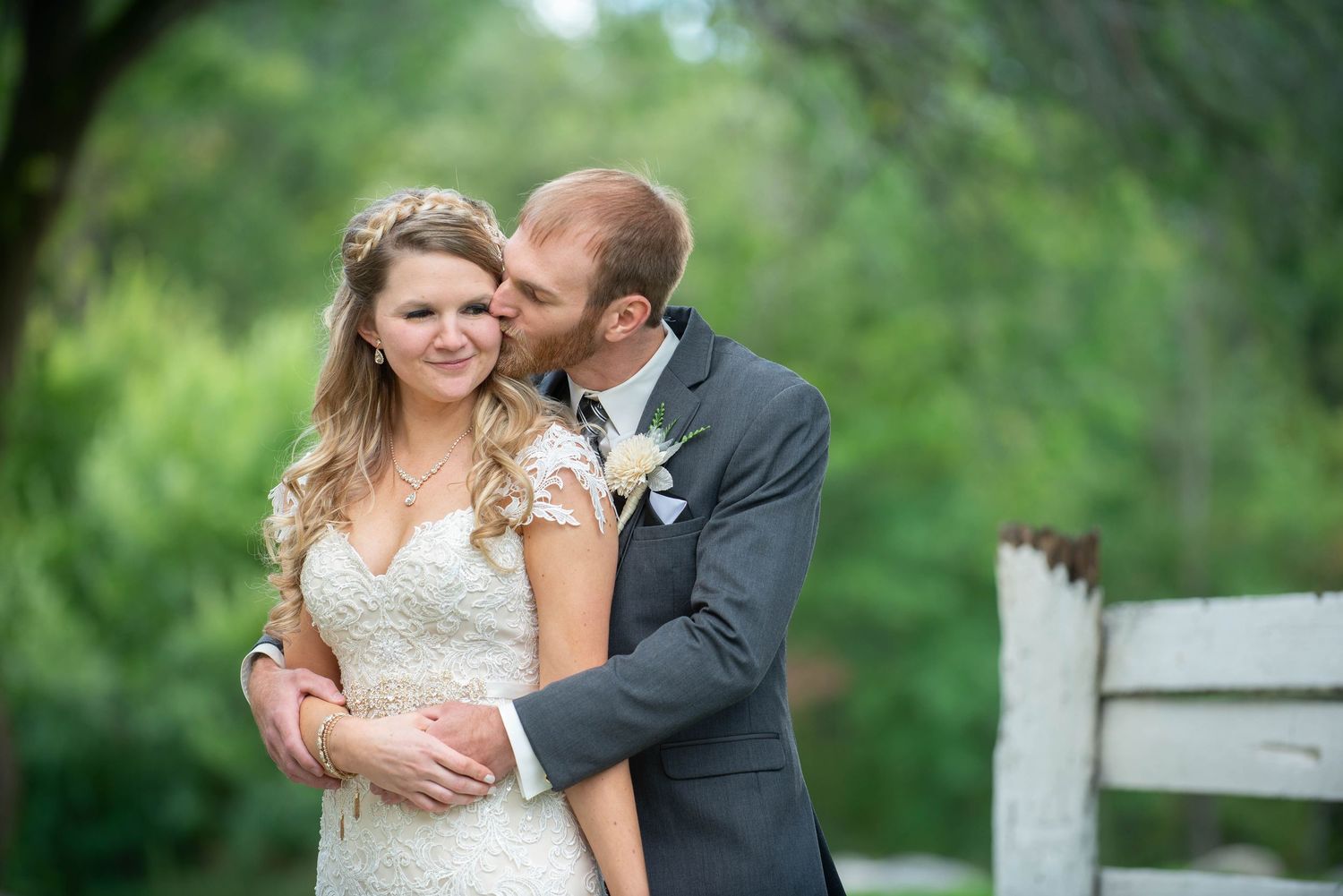 Newlywed couple embraces while posing for romantic portraits in a lush garden setting. Rum River Barn Milaca Minnesota Weddings
