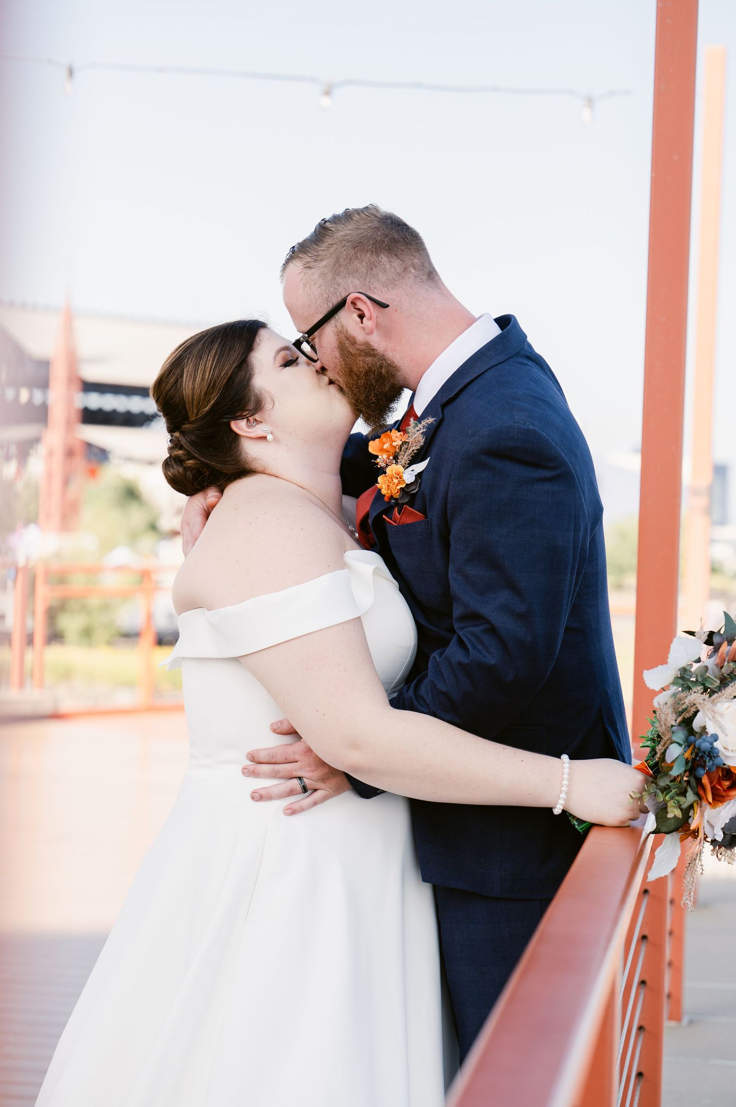 Pier B Duluth Wedding A romantic kiss between newlyweds in formal attire against a coral-colored backdrop.