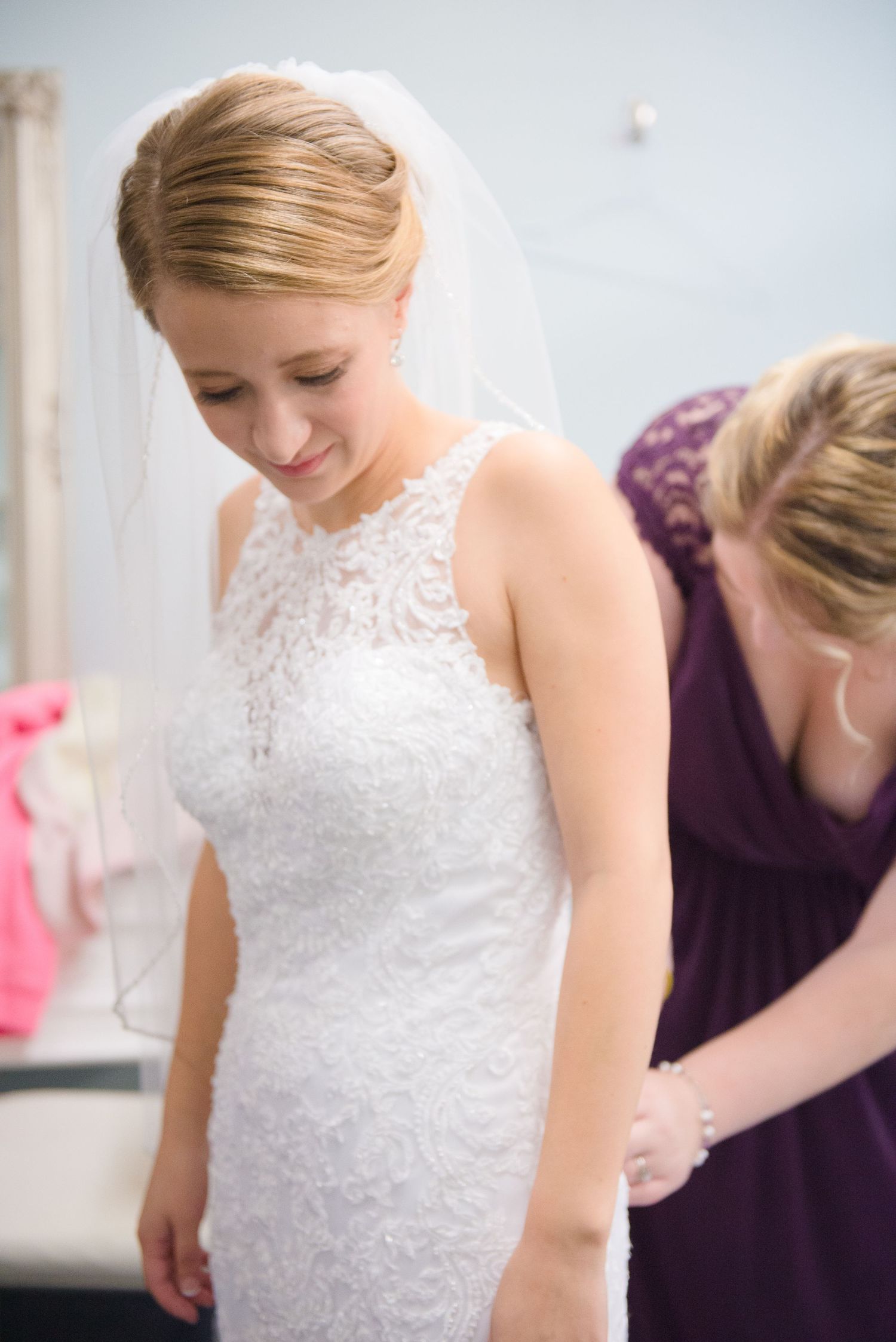 A close-up sequence showing a bride's lace wedding dress with purple-clad bridesmaids helping prepare for the ceremony. Andover wedding at M