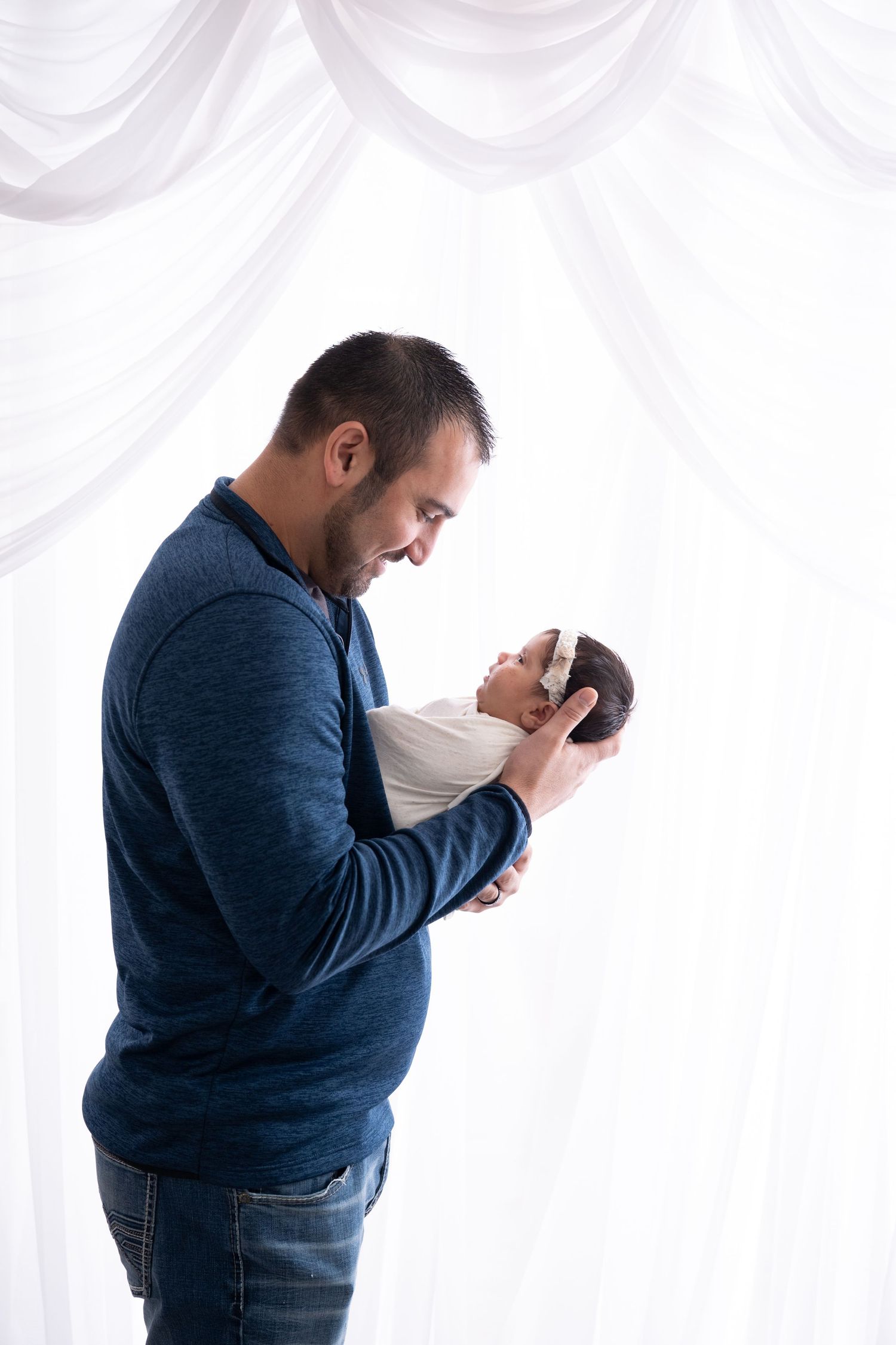 A tender moment between a parent and newborn against a white backdrop.