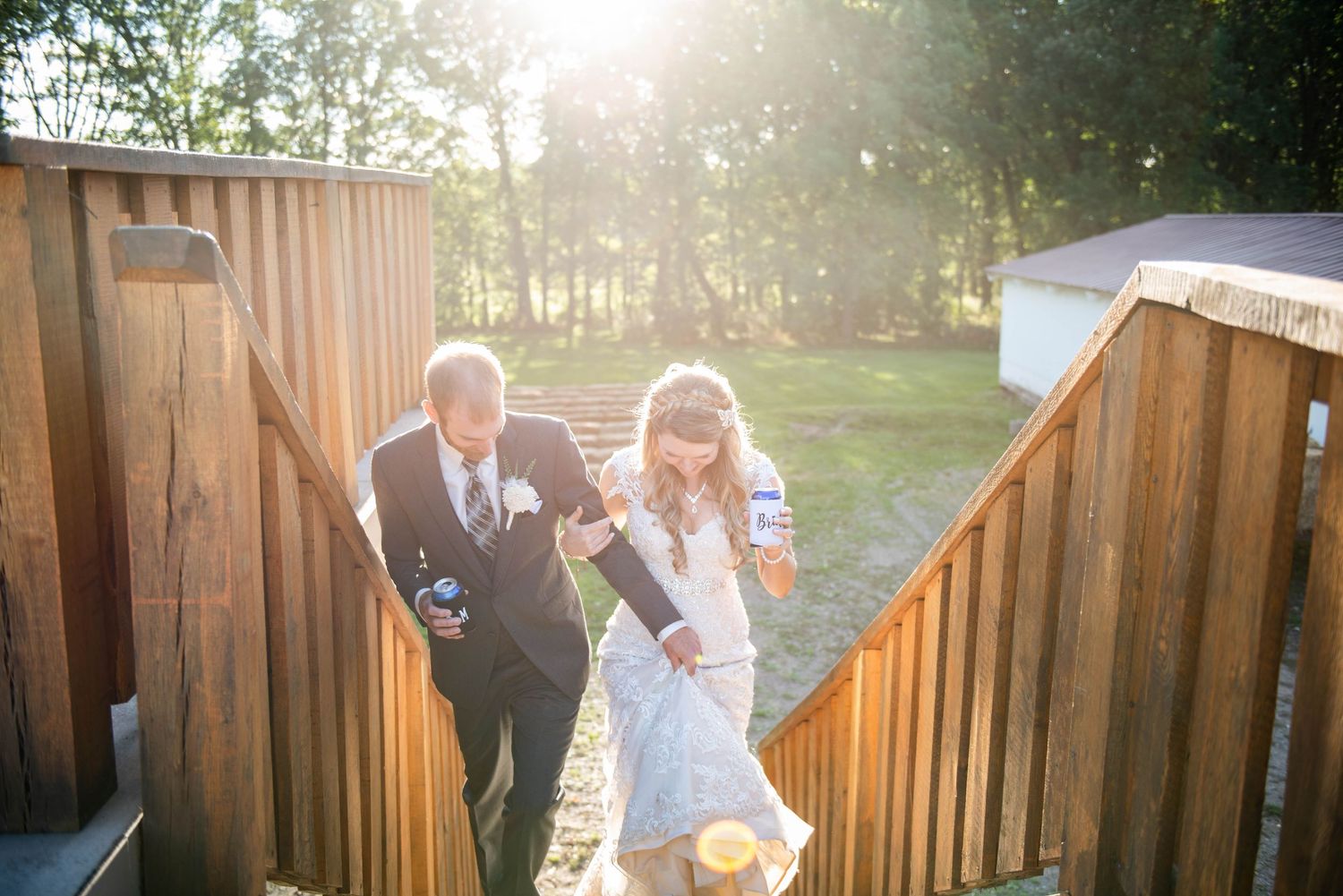 Couple climbs wooden staircase at sunset during wedding celebration. Rum River Barn Milaca Minnesota Weddings