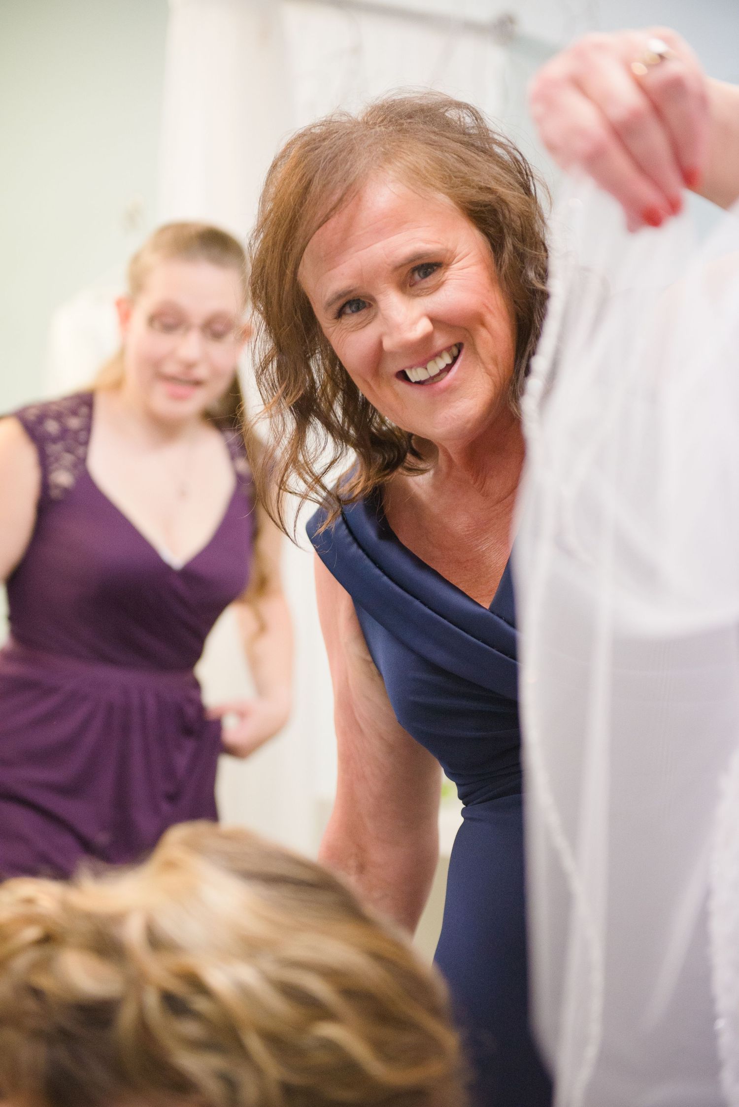 Wedding party members in purple and navy dresses share a joyful moment while getting ready. Andover wedding at Magestic Oaks Golf Club