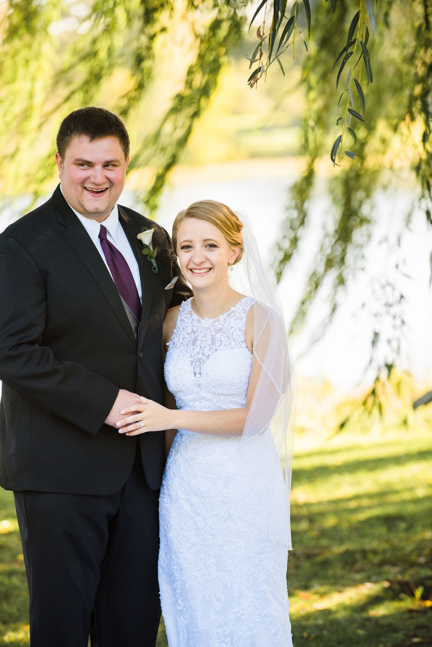 Newlywed couple poses under weeping willow trees for romantic outdoor wedding portrait. Andover wedding at Magestic Oaks Golf Club