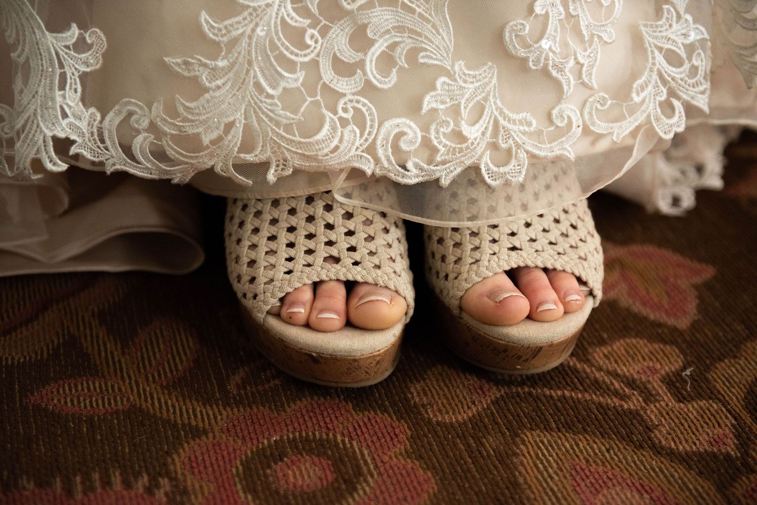 Bride's feet in cream crochet peep-toe sandals peeking beneath her wedding dress. Rum River Barn Milaca Minnesota Weddings