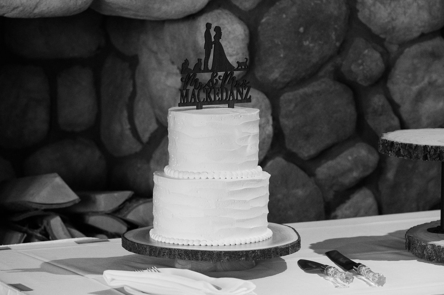 Wedding cake display with black and white tiers on stone backdrop.