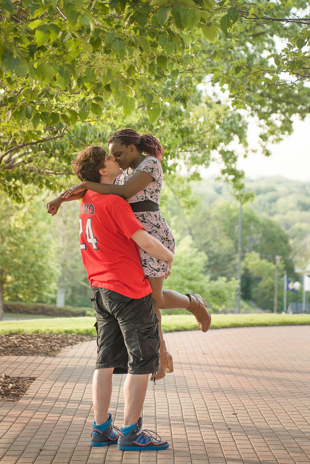 A sequence of embracing figures on a brick pathway surrounded by lush greenery and trees.