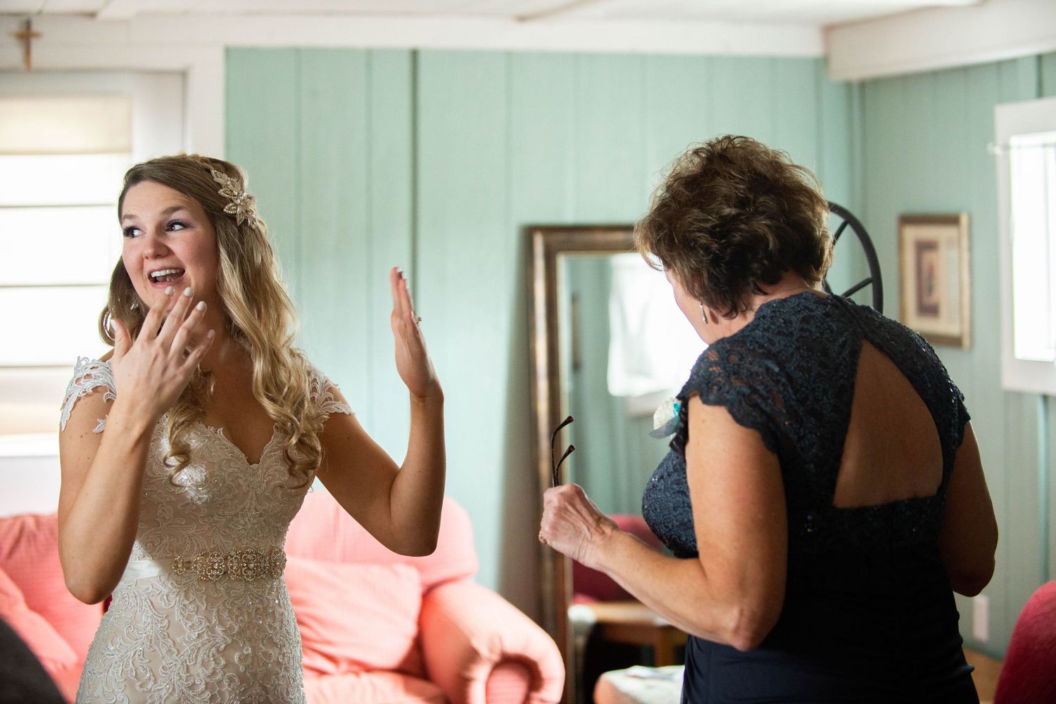 Candid moment during wedding preparations in a mint green room with natural lighting. Rum River Barn Milaca Minnesota Weddings