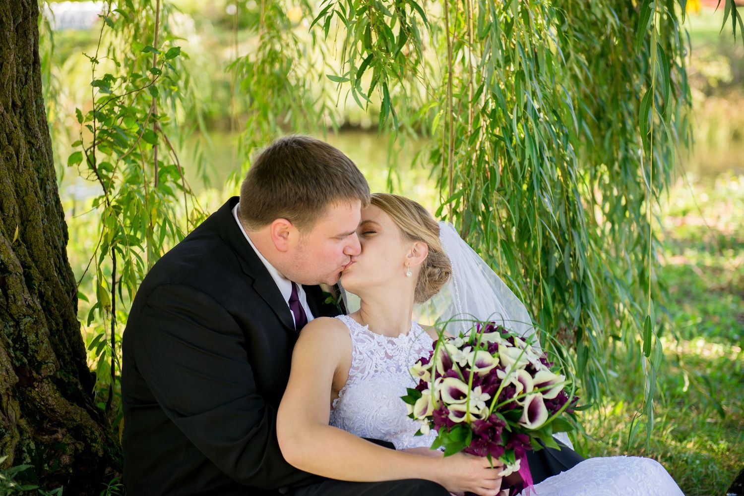 Wedding couple sharing romantic moments under weeping willow trees in a garden setting. Andover wedding at Magestic Oaks Golf Club