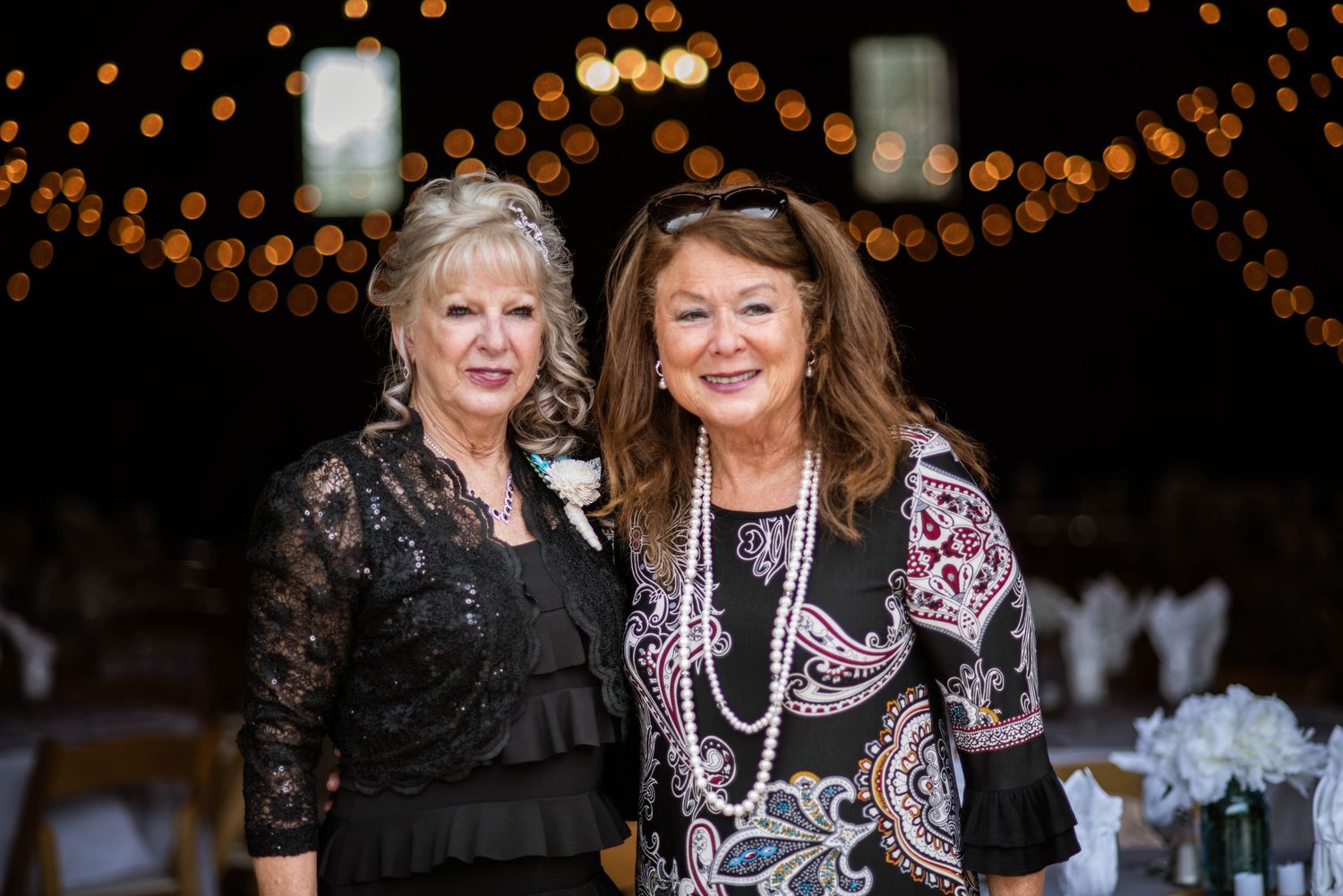 Two people embracing and laughing together at an evening event with sparkly lights in the background.