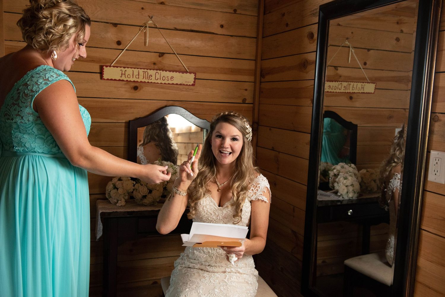 A moment of preparation in a rustic cabin with teal bridesmaid dress visible. Rum River Barn Milaca Minnesota Weddings