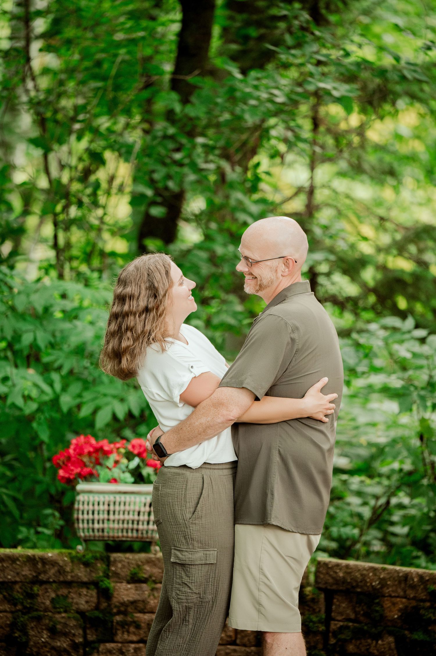 Clear Lake Family Photography: A happy couple shares a joyful moment together on a stone patio with vibrant greenery in the background.
