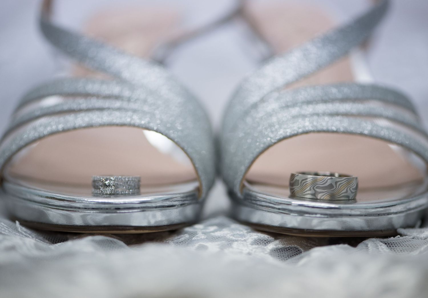 Elegant silver wedding rings displayed on sparkly bridal shoes. Andover wedding at Magestic Oaks Golf Club