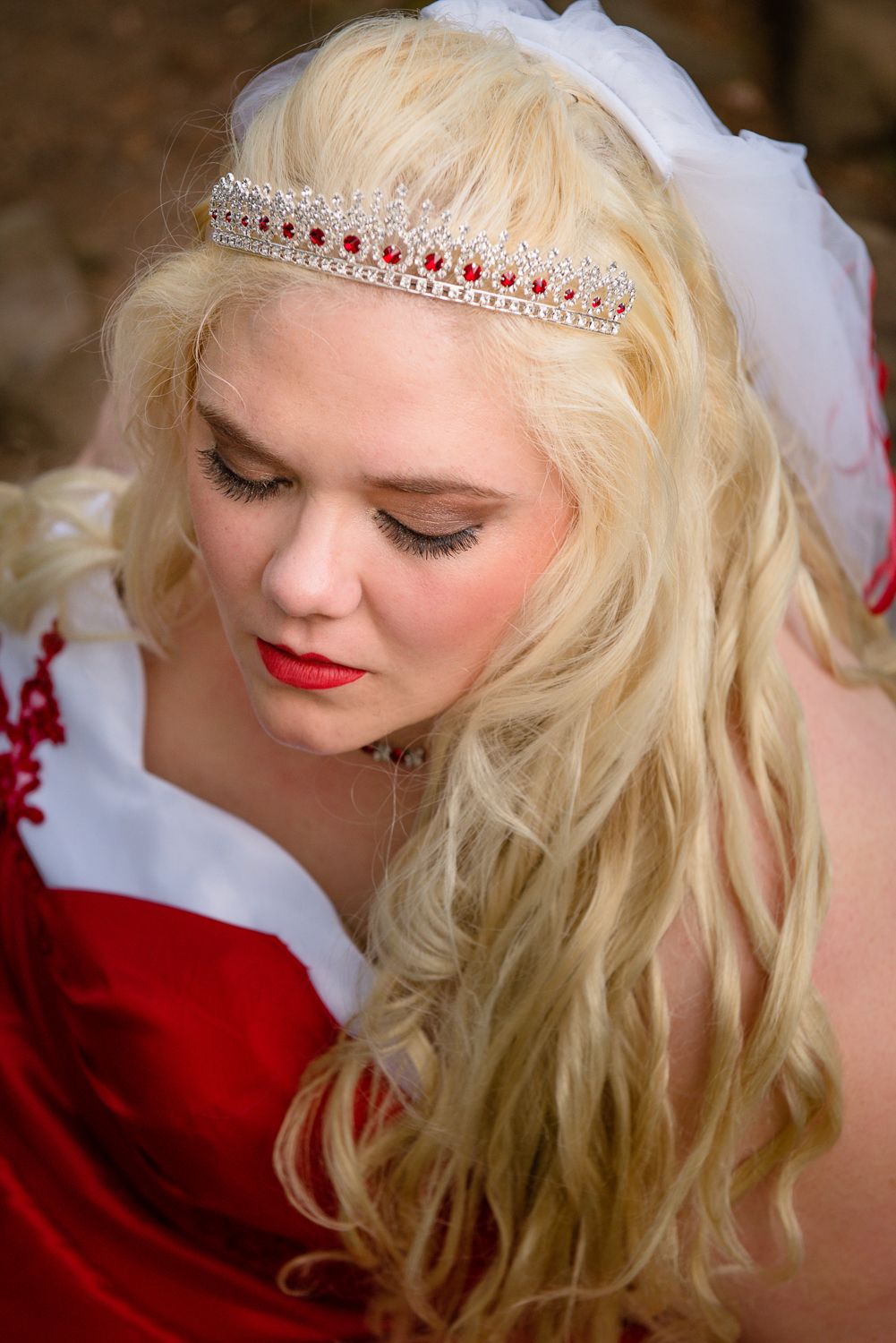 Delicate crystal tiara with red accents adorns flowing blonde curls alongside red and white holiday attire.