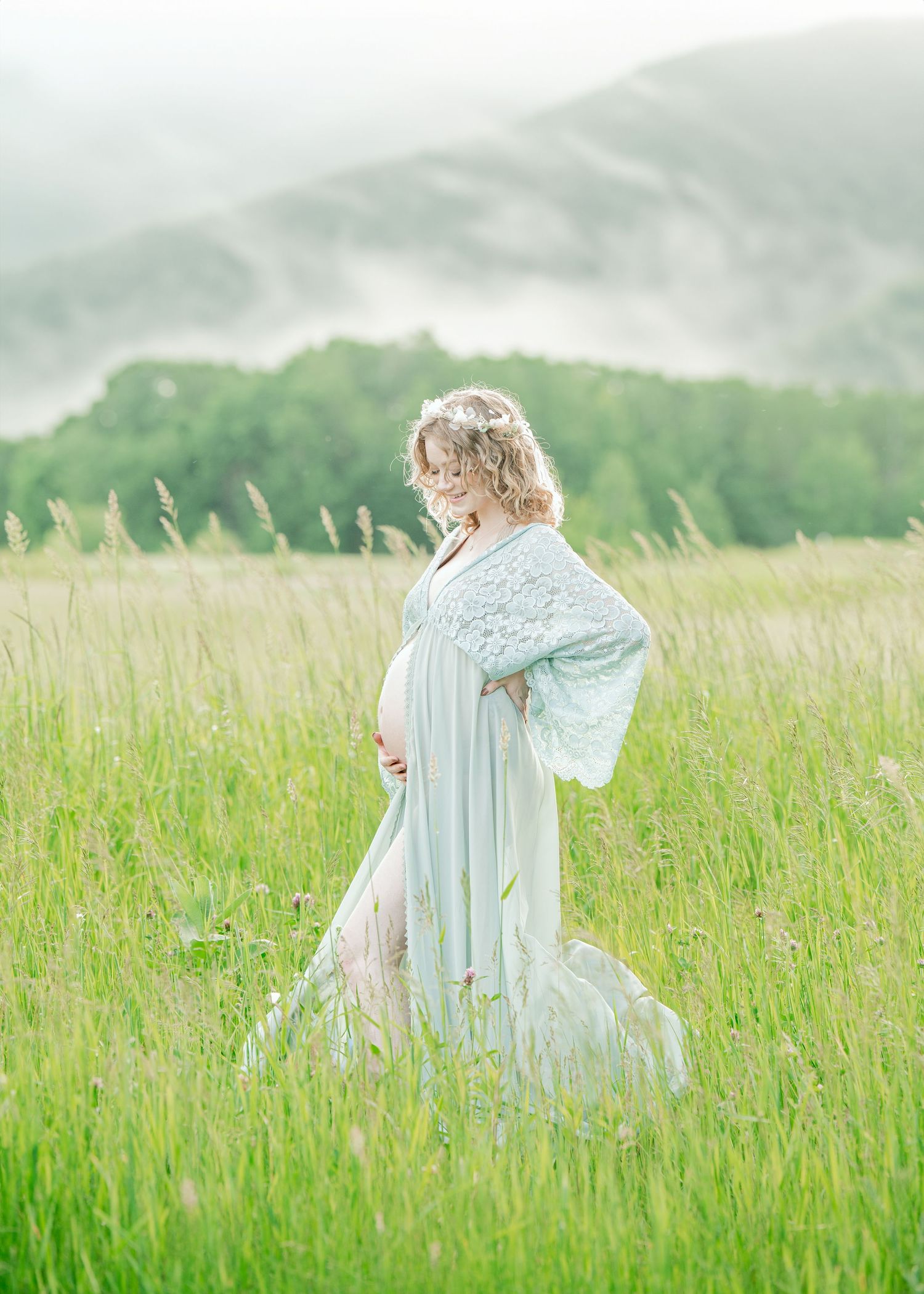 Ethereal maternity portrait in misty field with light blue flowing dress.