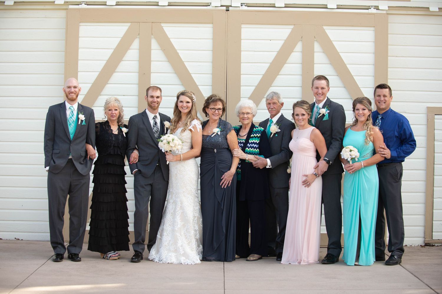 Formal wedding party group photo against white barn doors wearing mixed formal attire. Milaca Minnesota Weddings