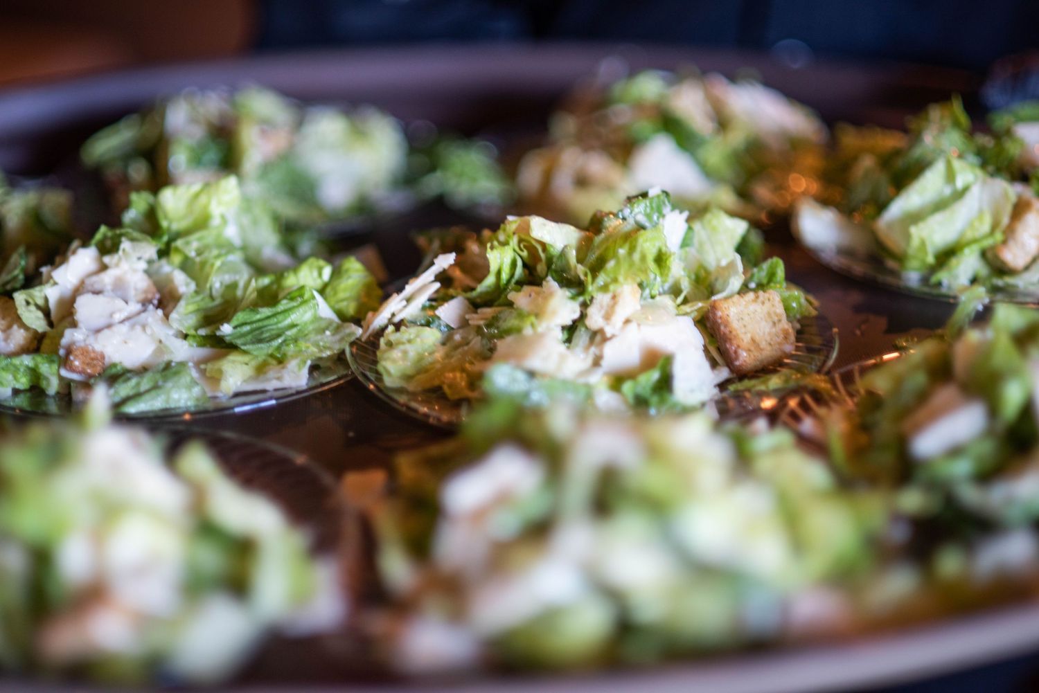 Fresh lettuce leaves and herbs arranged in rows on a rustic wooden surface create a vibrant culinary display.