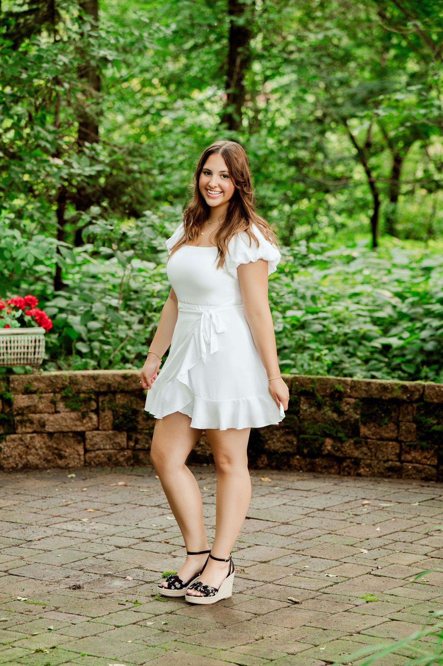 White dress captures movement on stone patio with green forest backdrop.