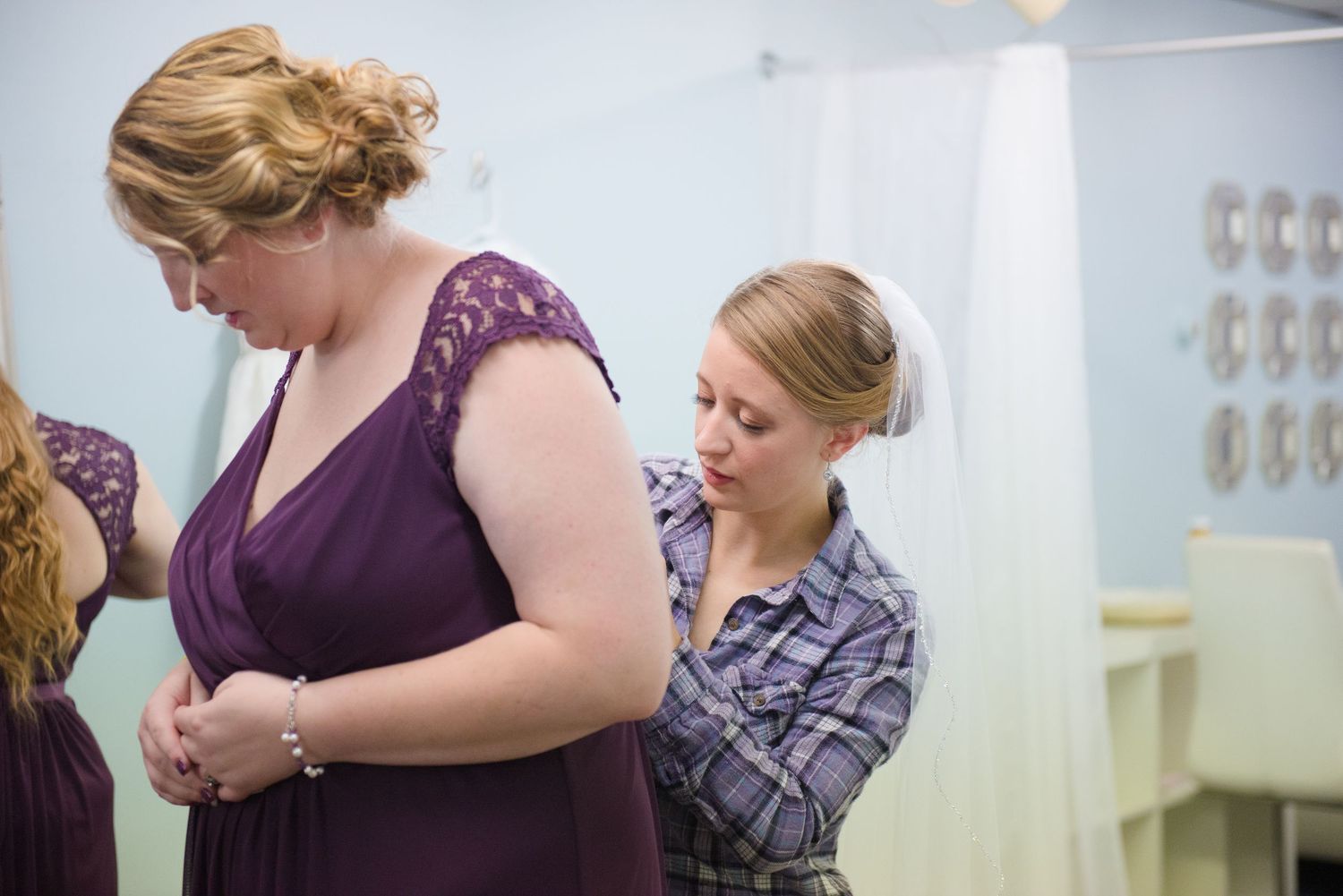 Dressing room scene showing someone in a purple bridesmaid dress being fitted and adjusted. Andover wedding at Magestic Oaks Golf Club