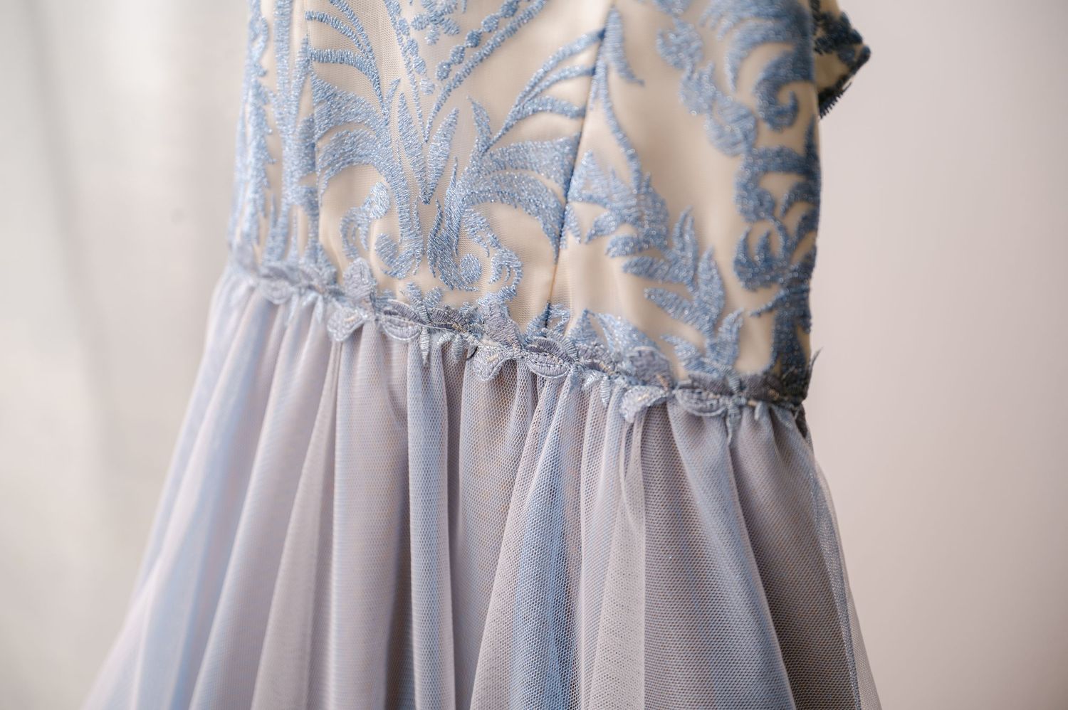 Close-up of a light blue formal dress featuring delicate lace bodice detail and gathered chiffon skirt.