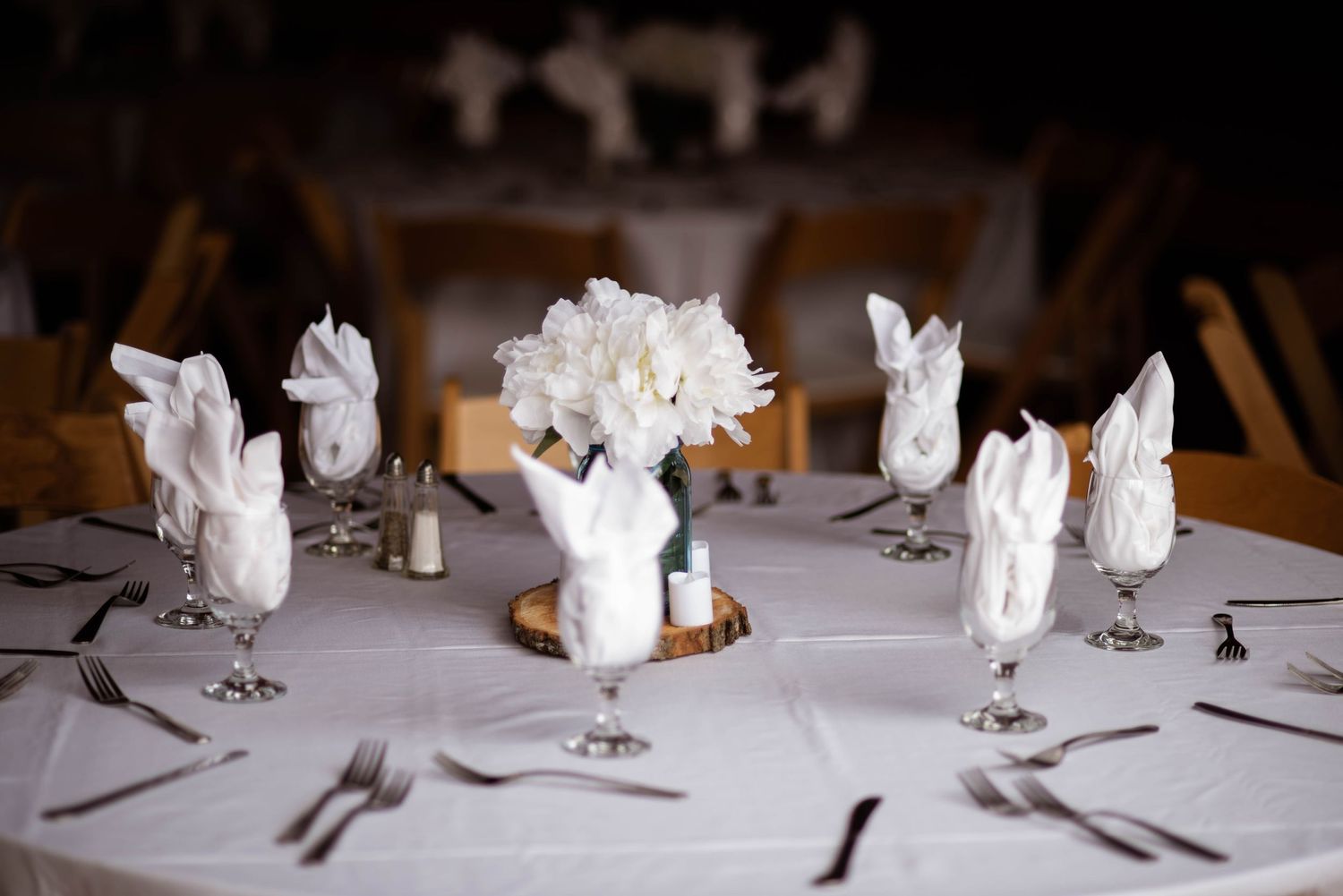 Wedding table centerpiece featuring elegant white floral arrangement with white bunny figurines on a tablecloth.