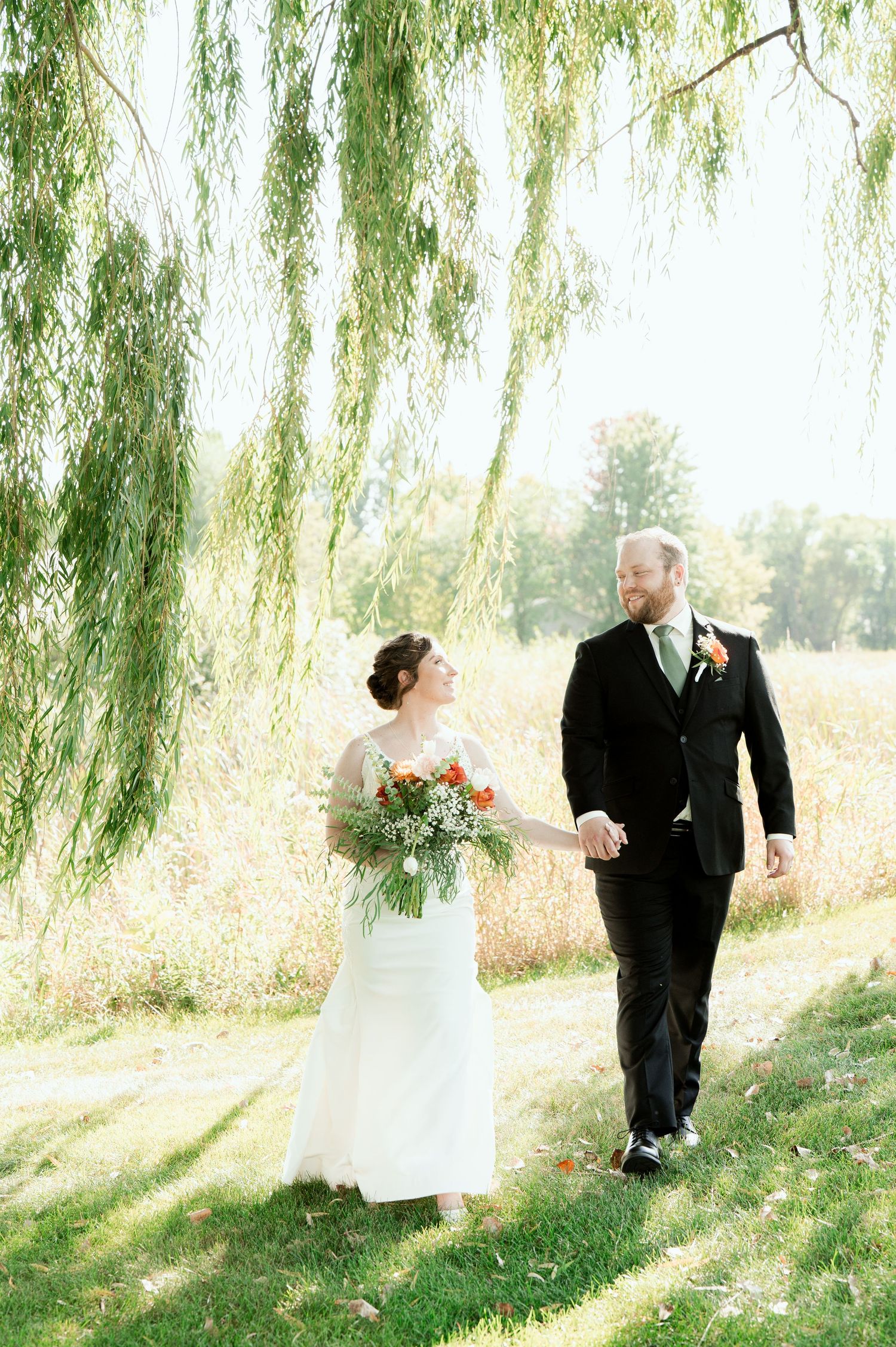 The Grands at Mulligans- Wedding Photos: MN. A romantic stroll under weeping willow trees with a garden bouquet of colorful flowers.
