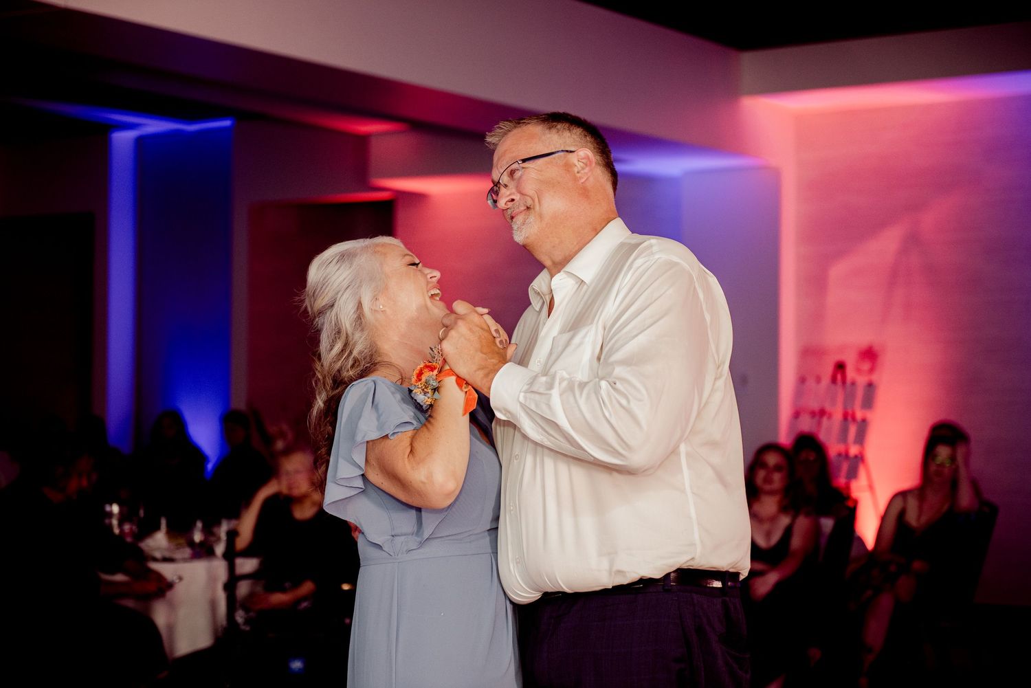 Pier B Duluth Wedding A sweet moment between dancers illuminated by blue and red lighting at an evening reception.