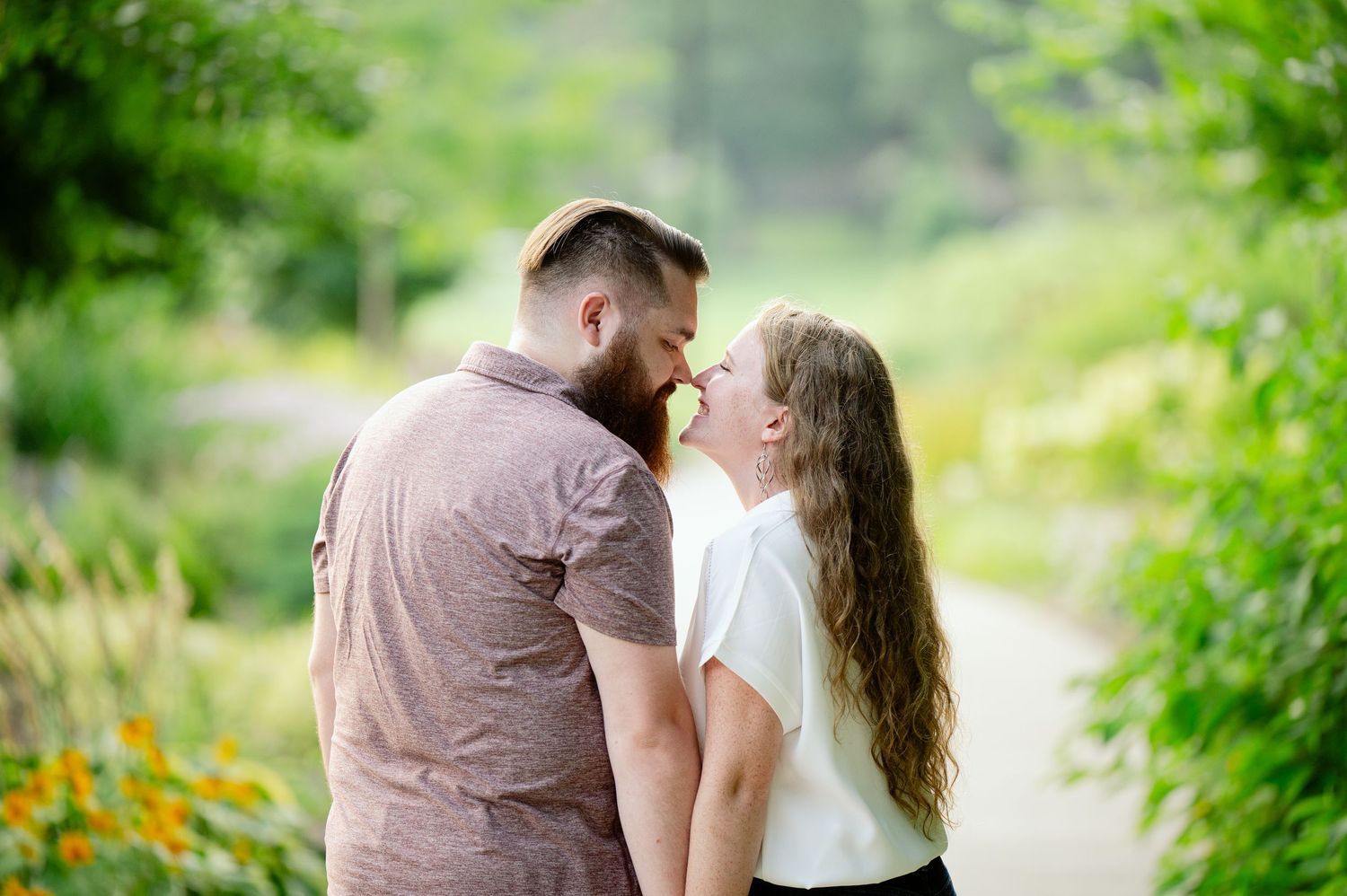 Romantic couple embracing in a lush garden setting with vibrant greenery and natural lighting.