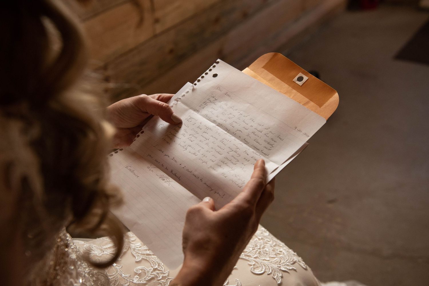 Woman's hands hold a small paper note while getting ready in a bridal preparation setting. Rum River Barn Milaca Minnesota Weddings