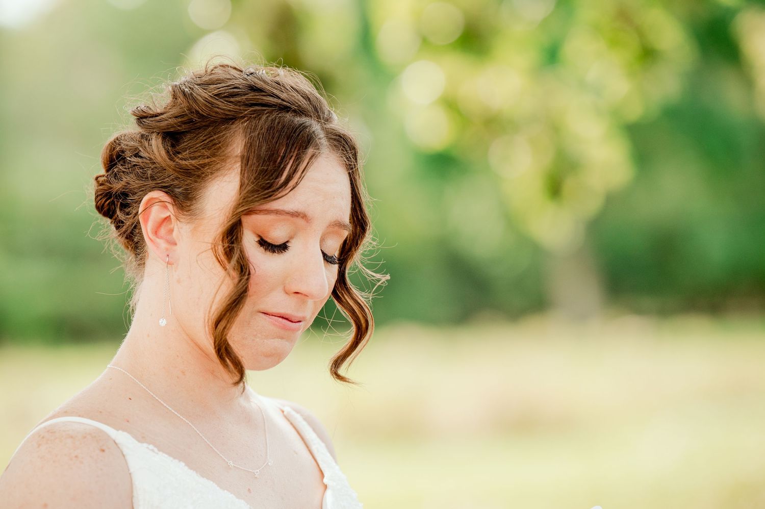 The Grands At Mulligans. Private vows soft lighting and a natural outdoor background featuring upswept hairstyle and white dress.