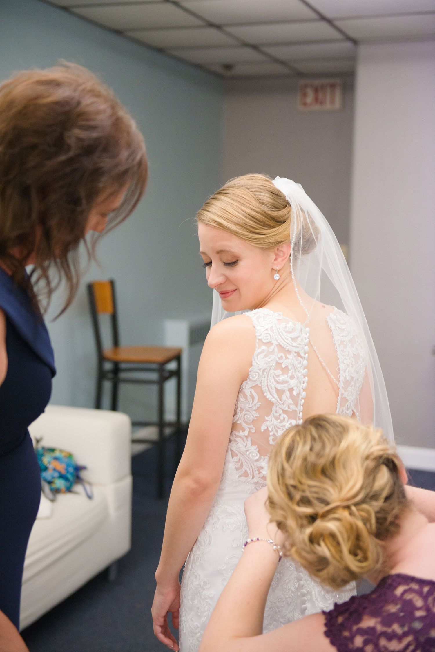 Wedding party helps with final adjustments to a detailed lace wedding gown and veil. Andover wedding at Magestic Oaks Golf Club