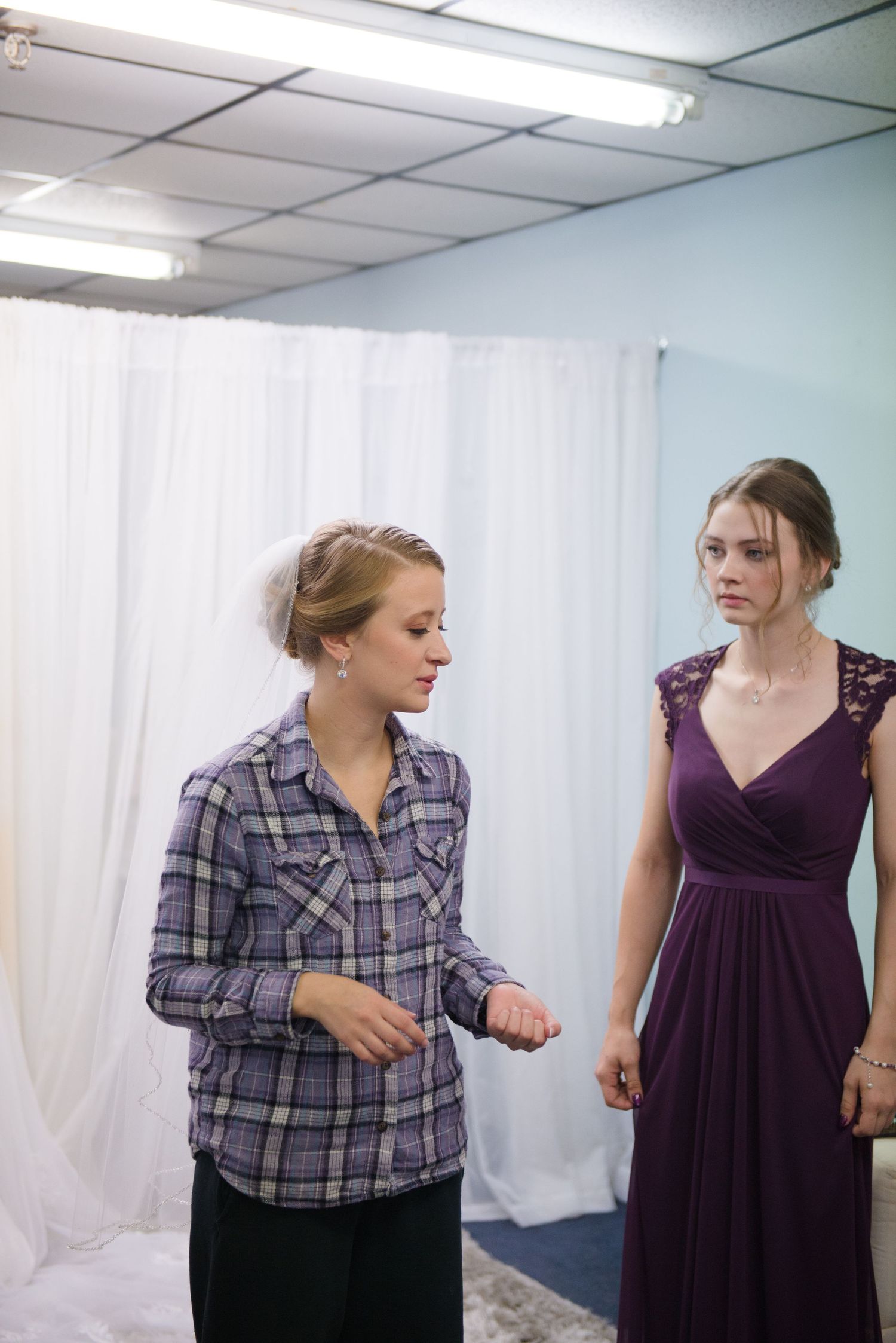 Two people in a dressing room, one wearing a plaid shirt and one in a purple formal dress. Andover wedding at Magestic Oaks Golf Club