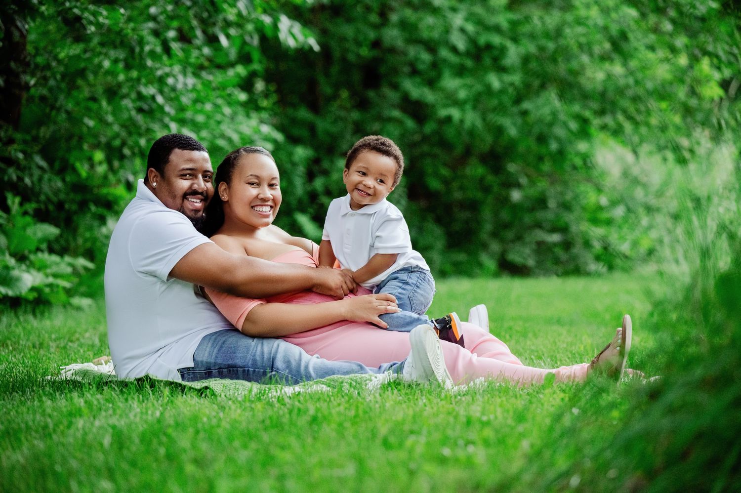 Family sitting together on grass enjoying a picnic outdoors in a park setting.