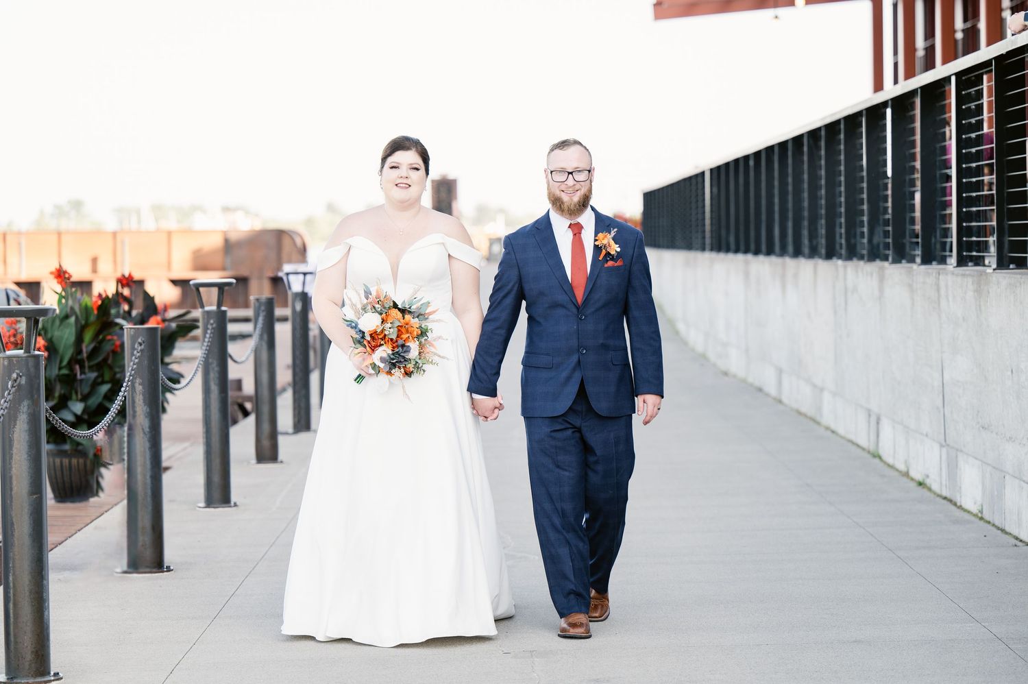 Pier B Duluth Wedding Bride and groom pose for wedding photos along an outdoor walkway with modern architectural elements.