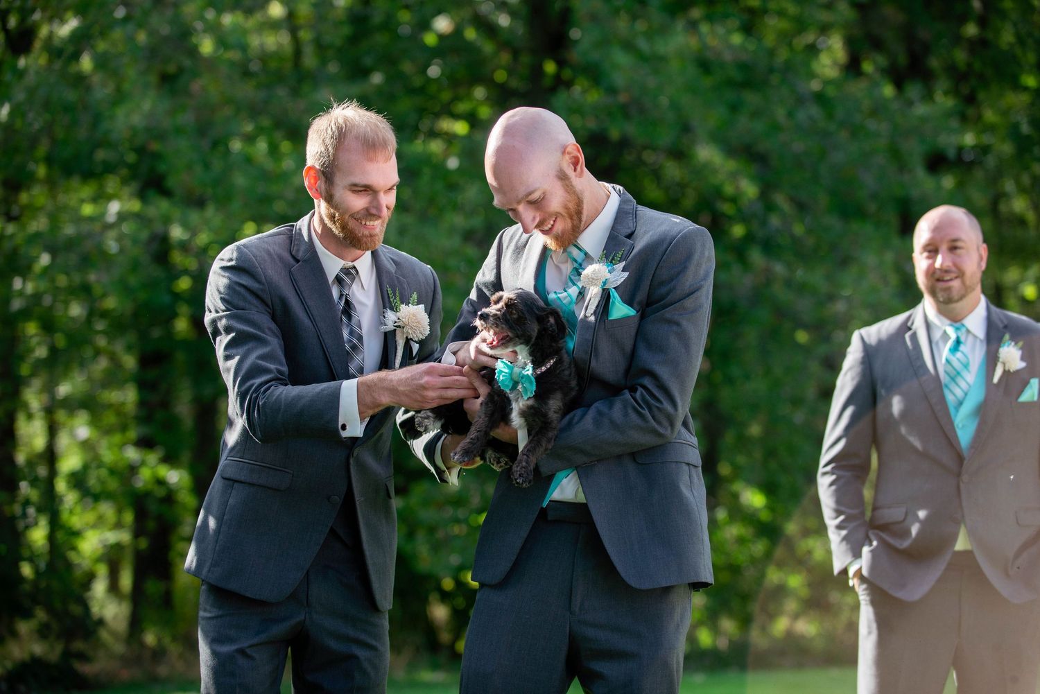 Groomsmen in suits sharing a light moment during outdoor wedding festivities. Rum River Barn Milaca Minnesota Weddings