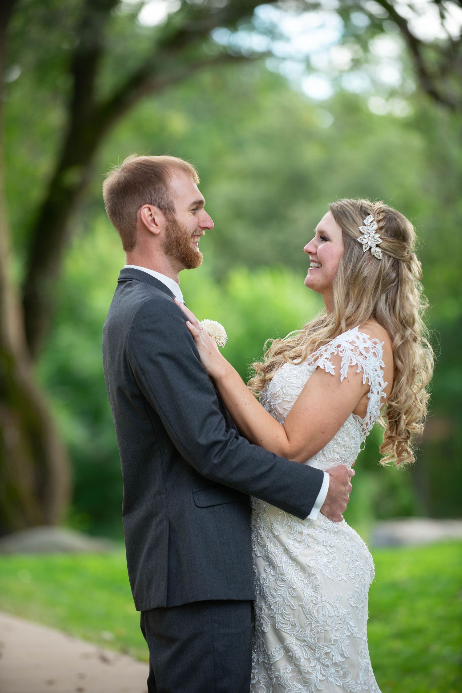 A joyful wedding couple embraces while sharing a laugh in a garden setting. Rum River Barn Milaca Minnesota Weddings