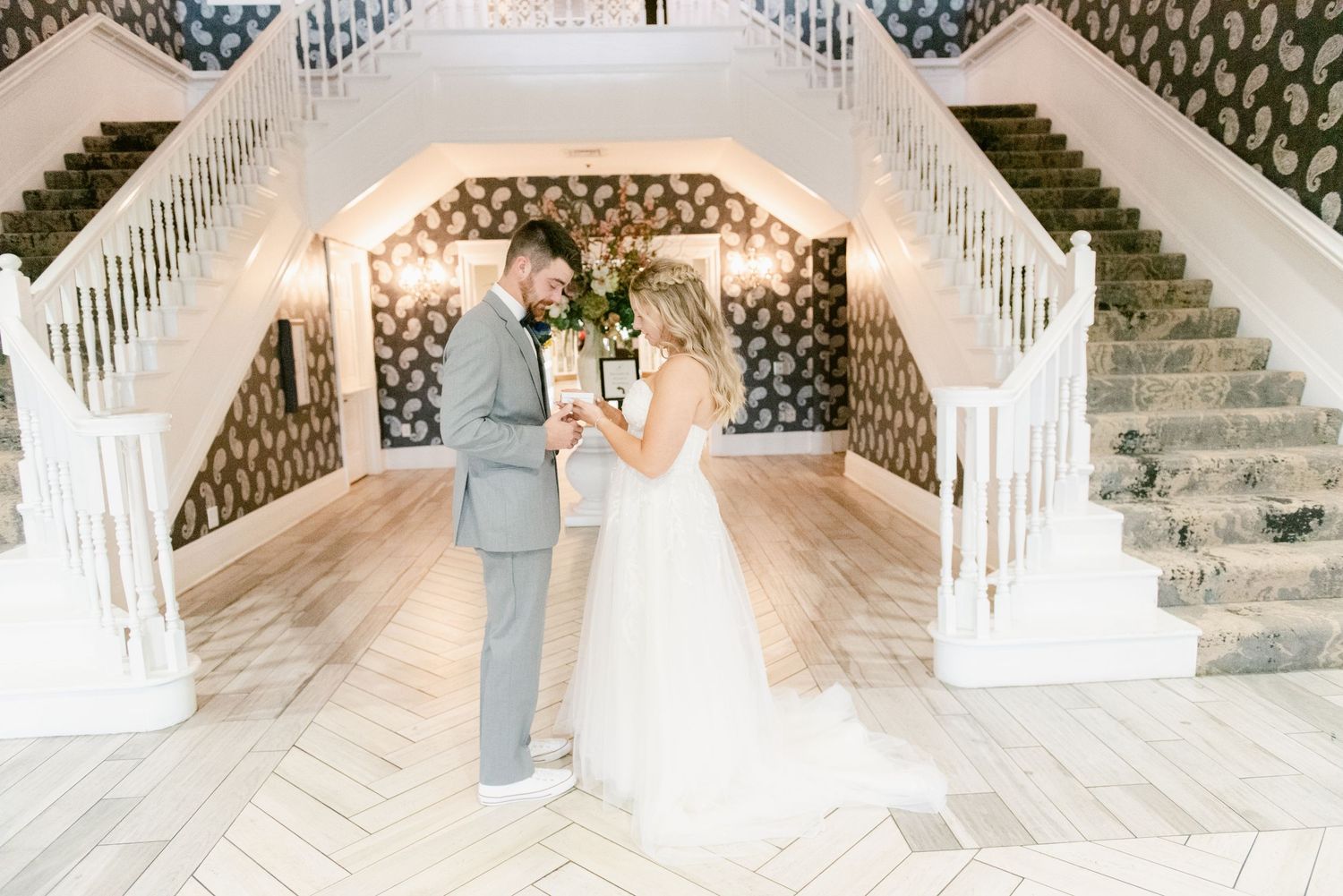 Interior view of wedding venue featuring a sweeping white staircase and elegant patterned walls.