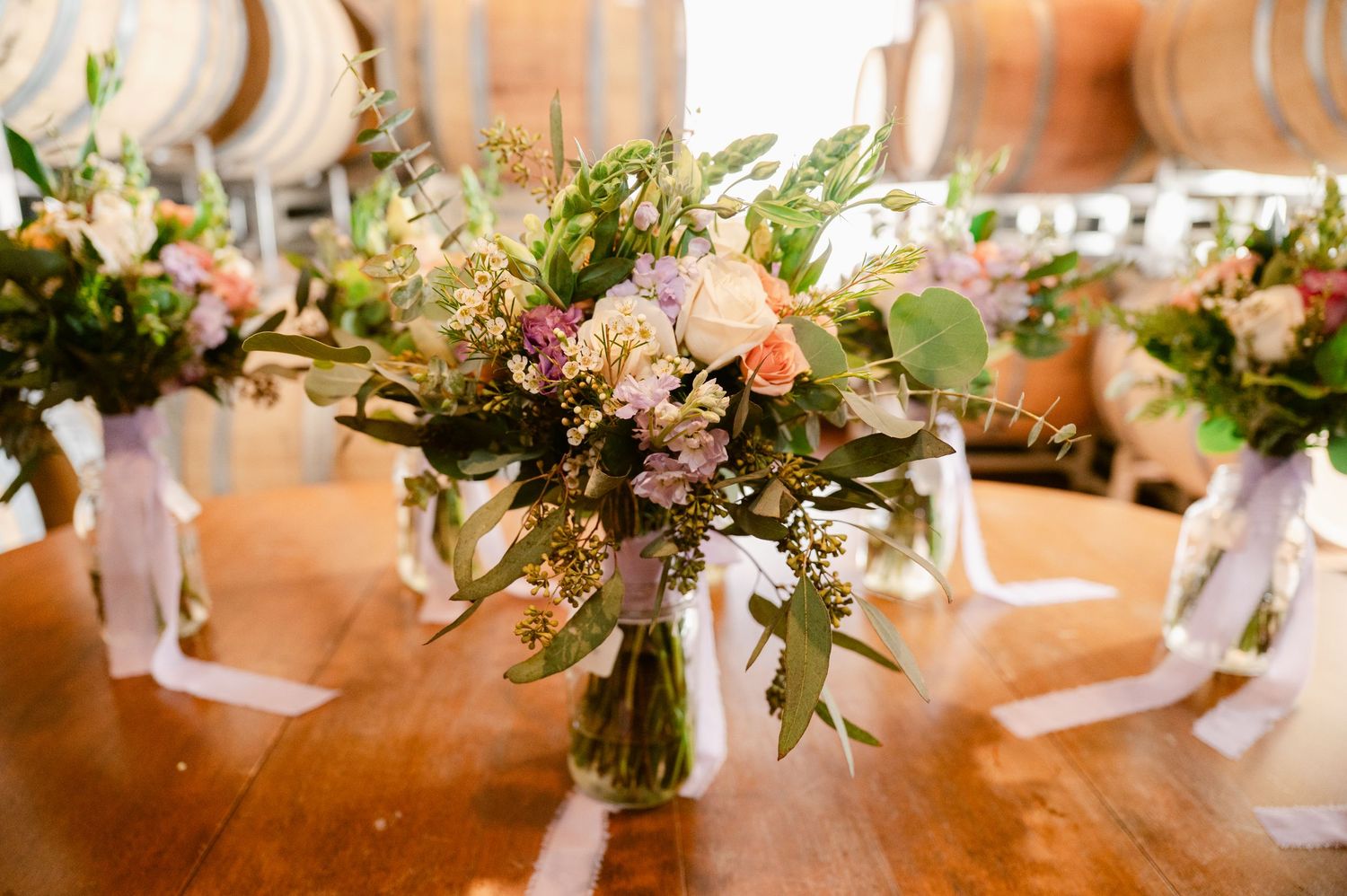 Wedding reception table settings with elegant floral centerpieces and pink accents create a romantic ambiance.