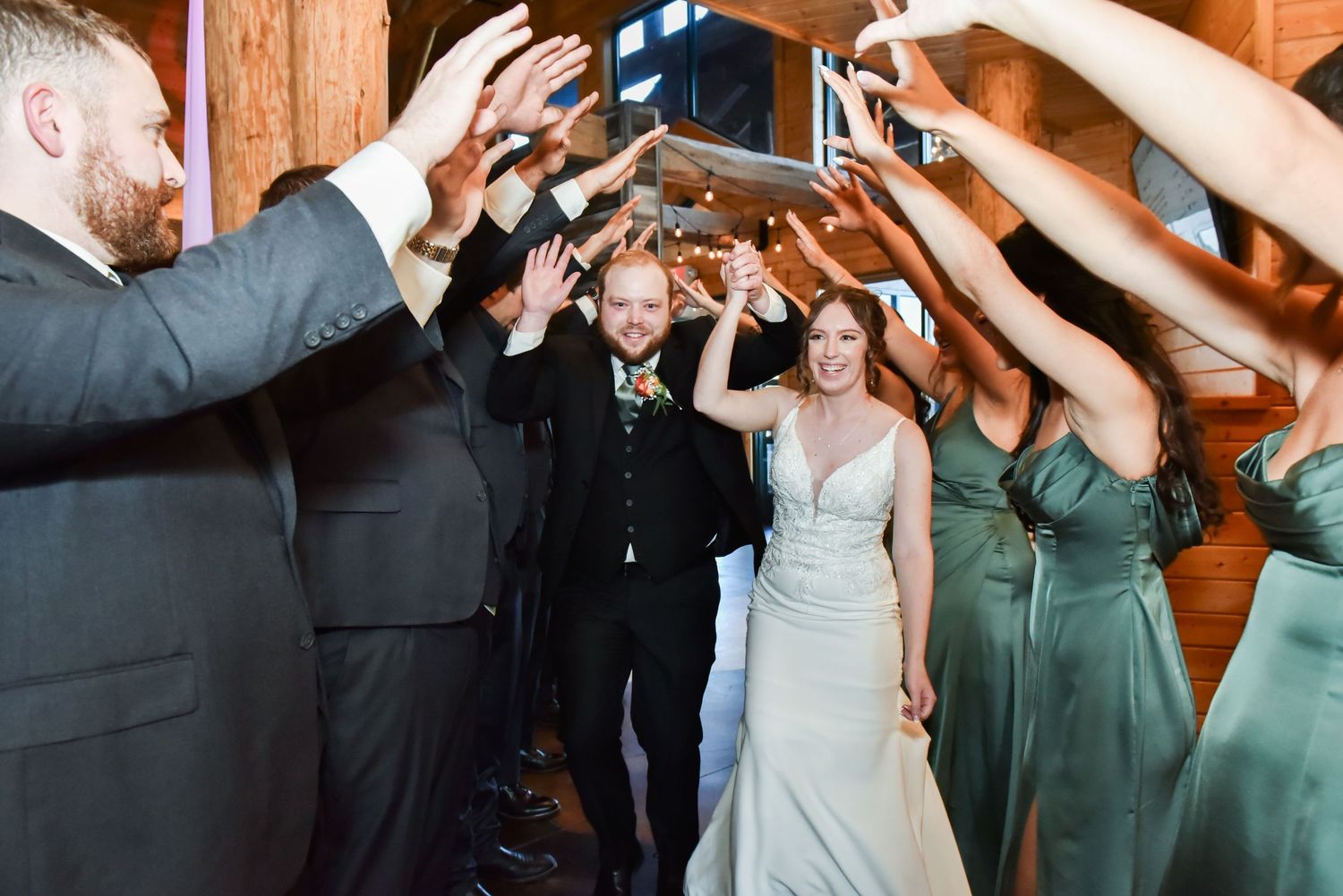 The Grands At Mulligans. The bridal party creates a walkway arch with raised arms as a bride and groom pass through during their reception.