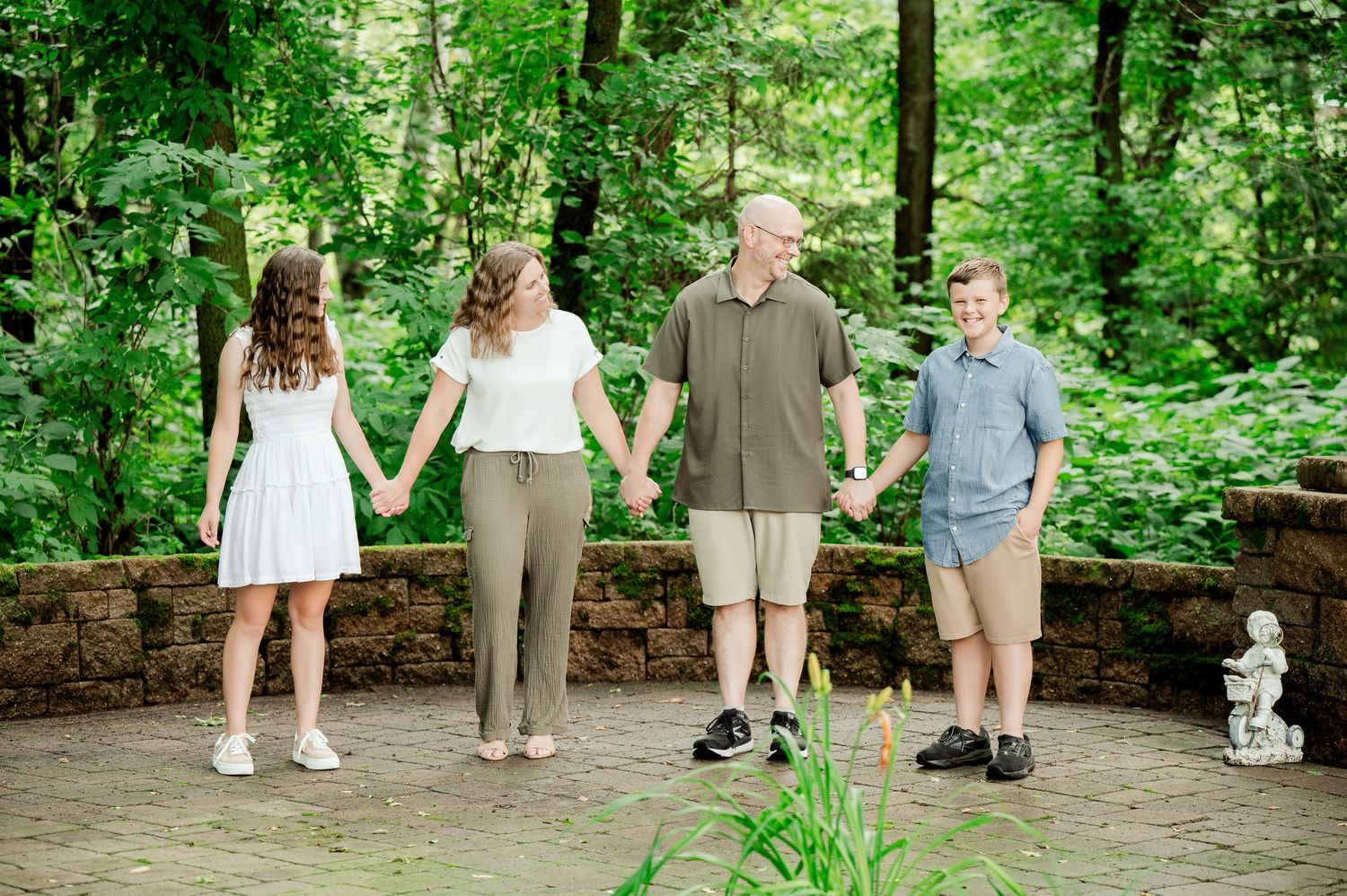 A group stands against a lush green forest backdrop during a casual outdoor photo session.