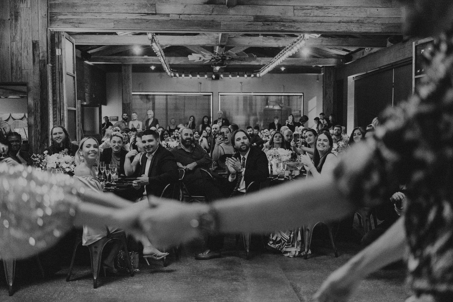 A black and white panoramic photograph shows a crowded ballroom filled with seated guests at formal tables.