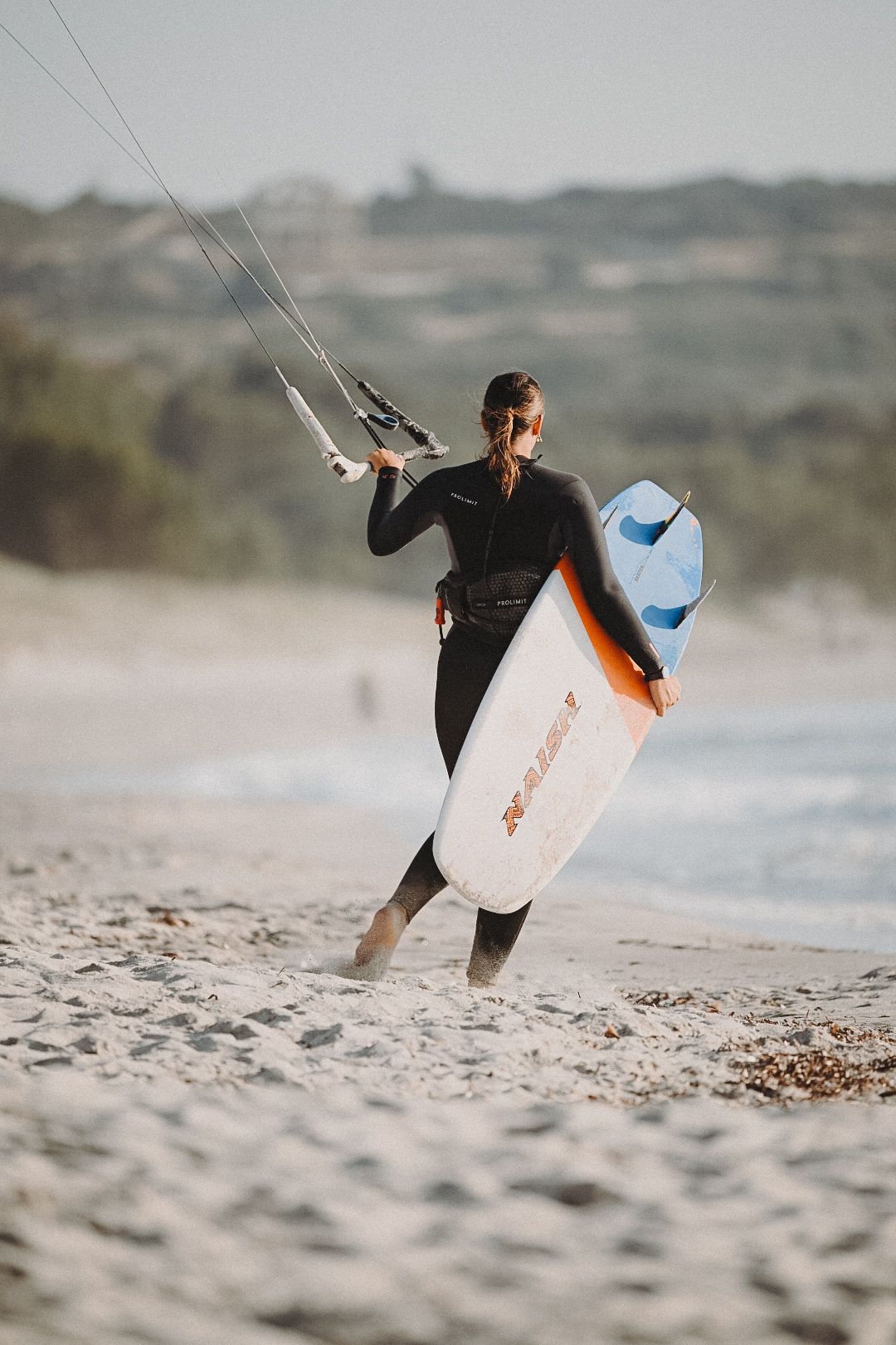 A woman walking on the beach to go kitesurfing in Mastichari, Greece