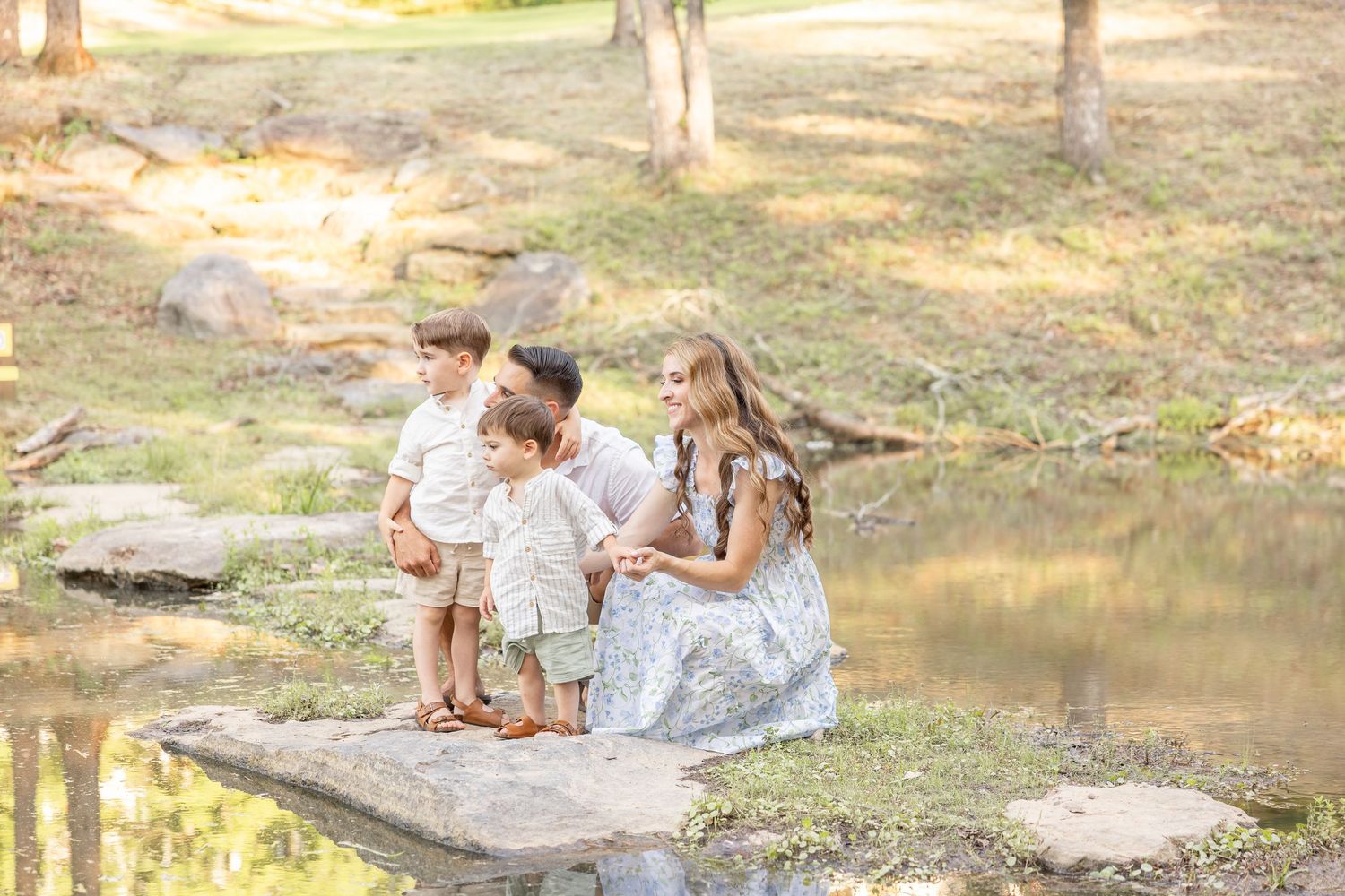 Child and parent exploring a stream or creek bed in a natural outdoor setting during golden hour.