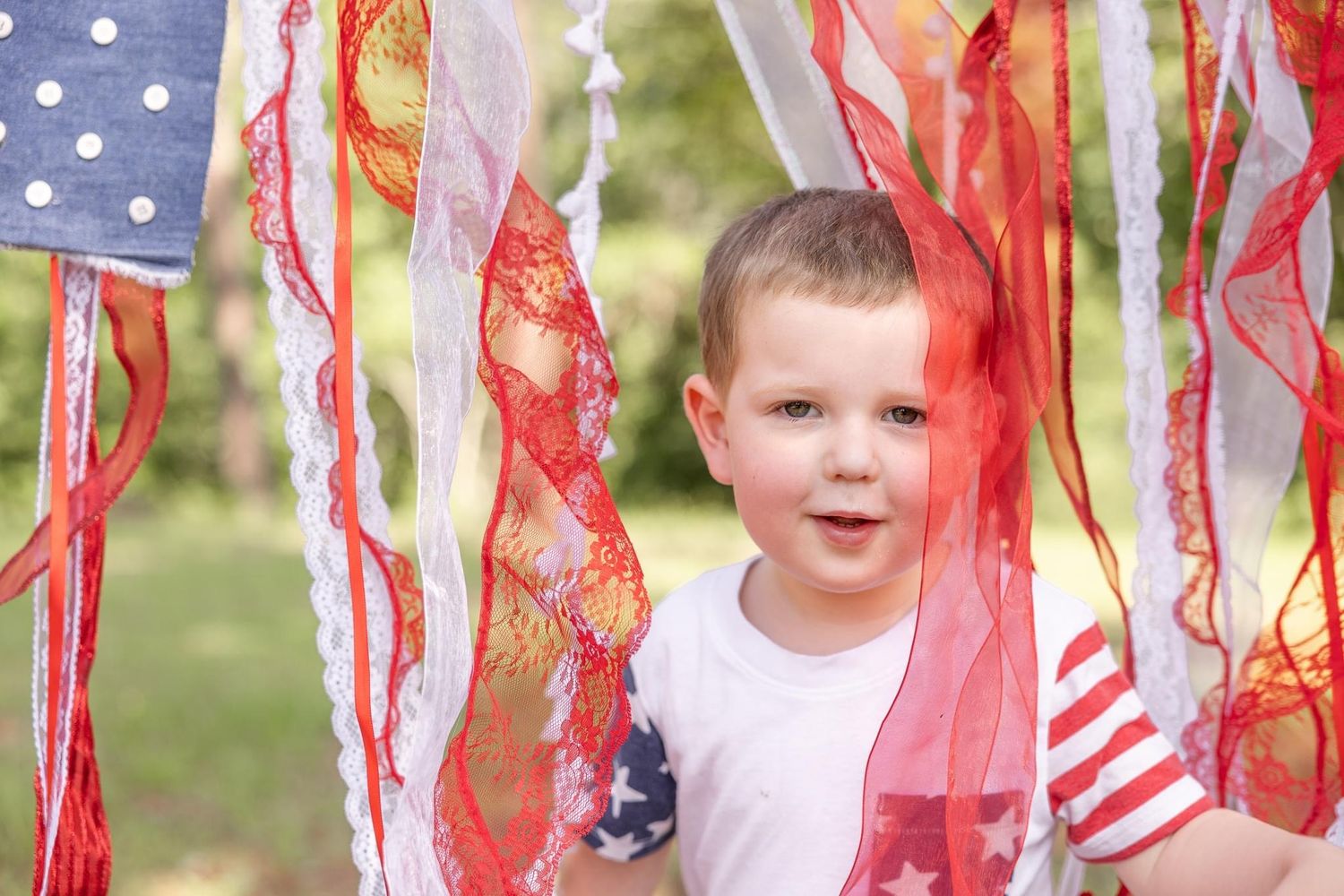 Children wave red and white streamers while celebrating outdoors on a sunny day.