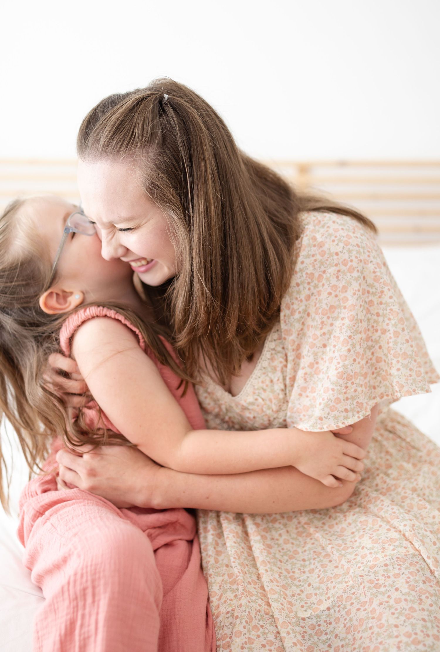 A tender moment of playful affection and laughter between parent and child wearing floral and pink outfits.