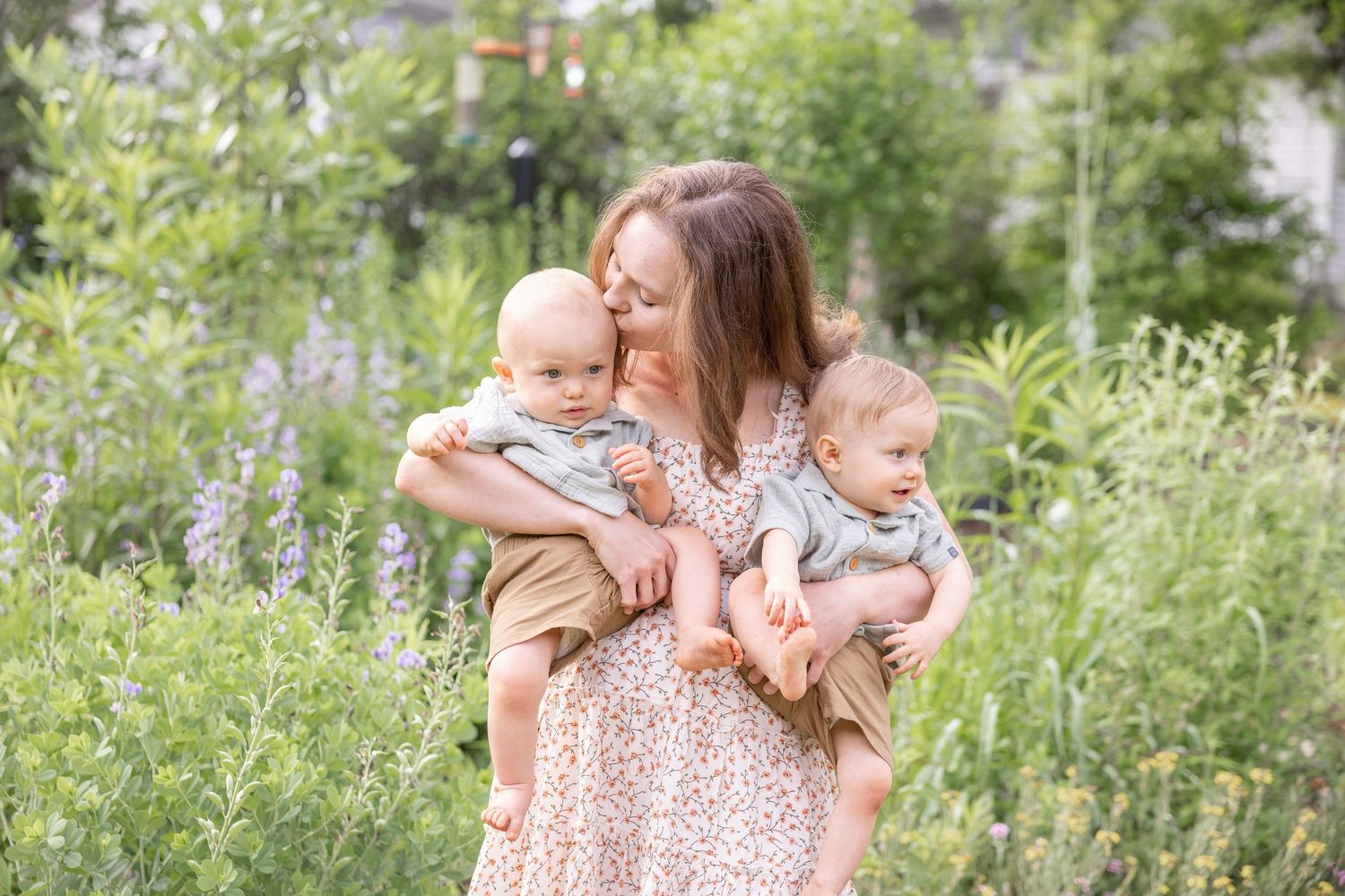 A family enjoying a sweet moment together in a lush garden setting with tall grasses and greenery.