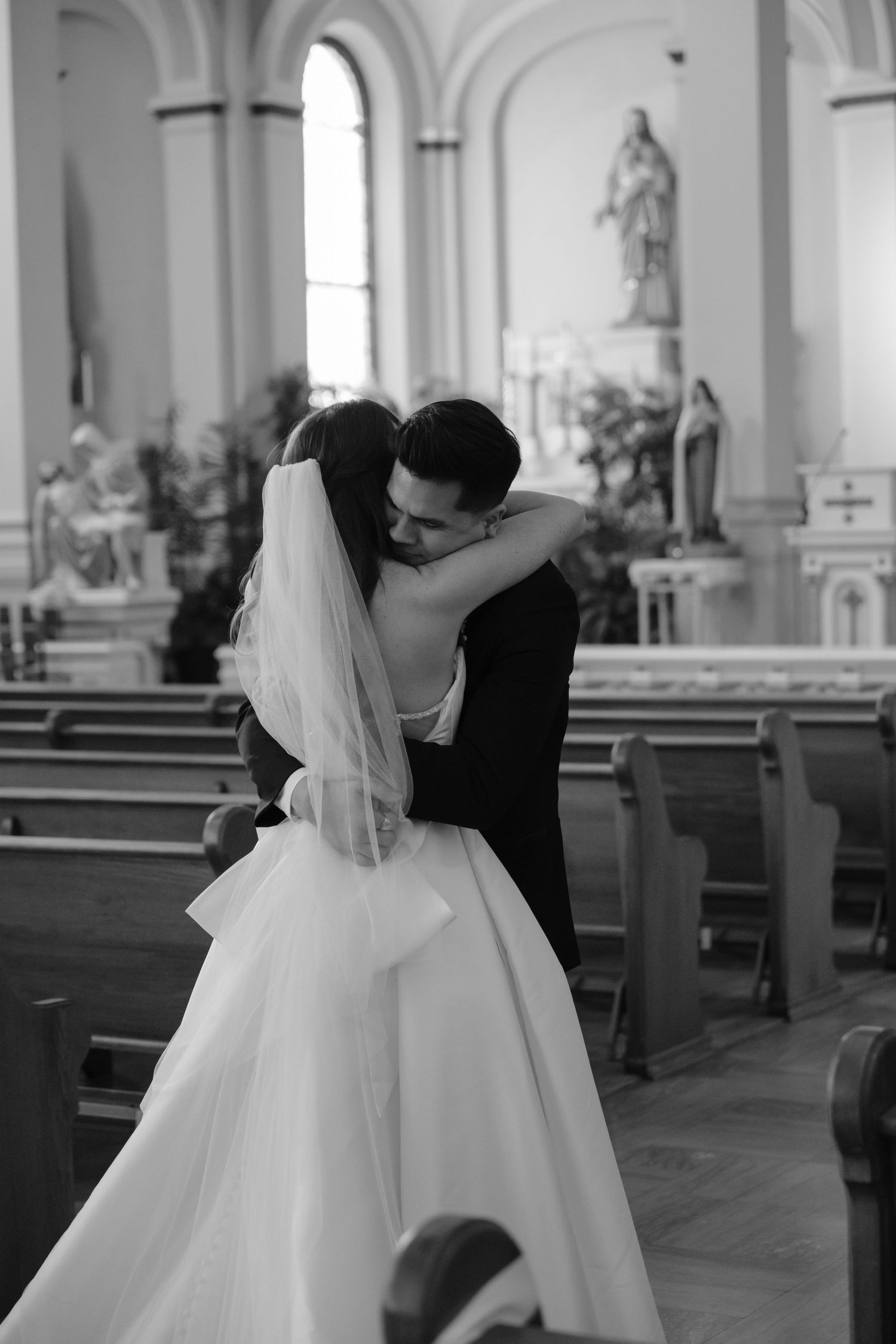 An intimate black and white wedding moment captured inside a traditional church sanctuary.