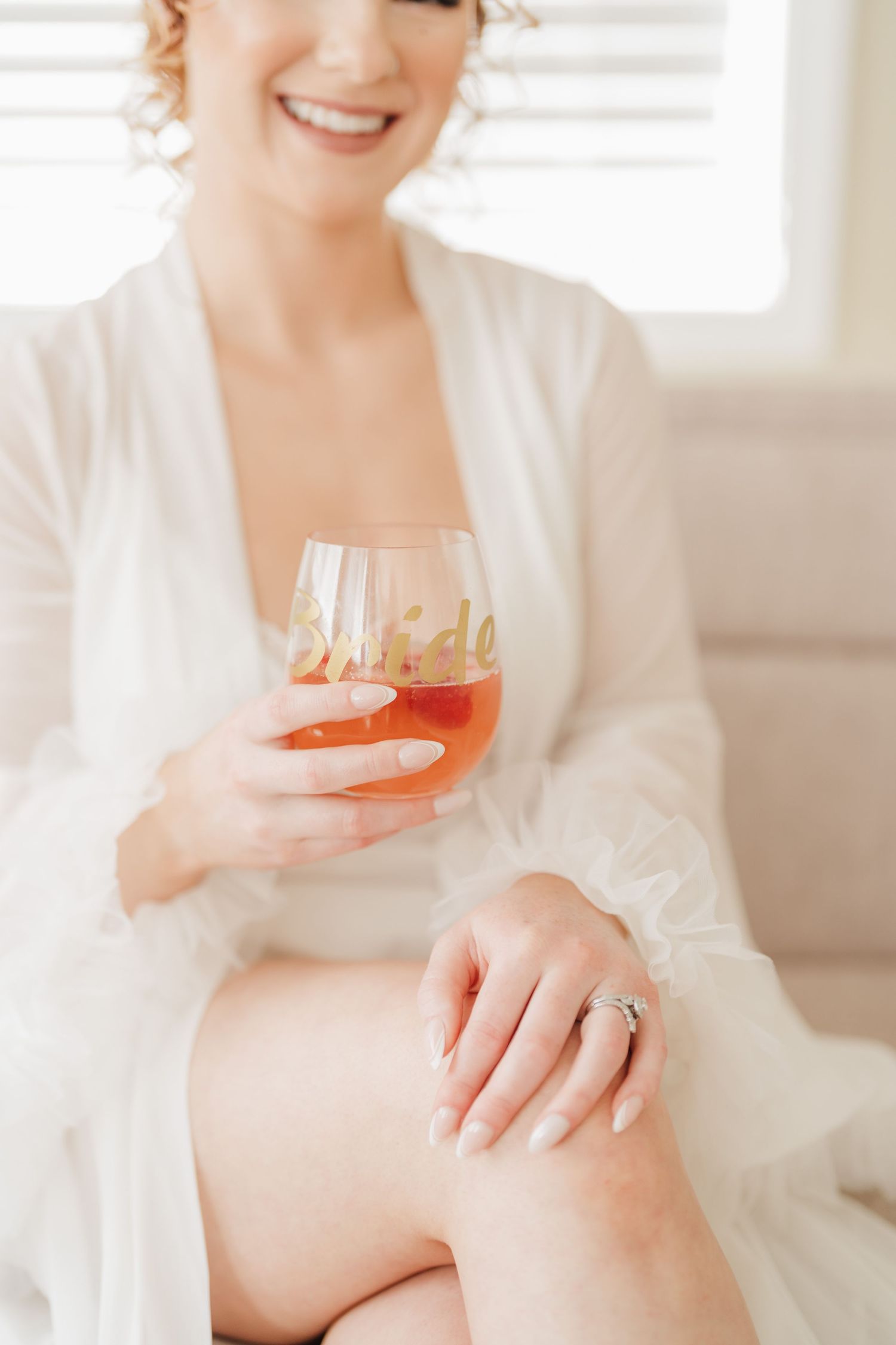 Close-up showing a wedding ring and cocktail glass during bridal preparations.